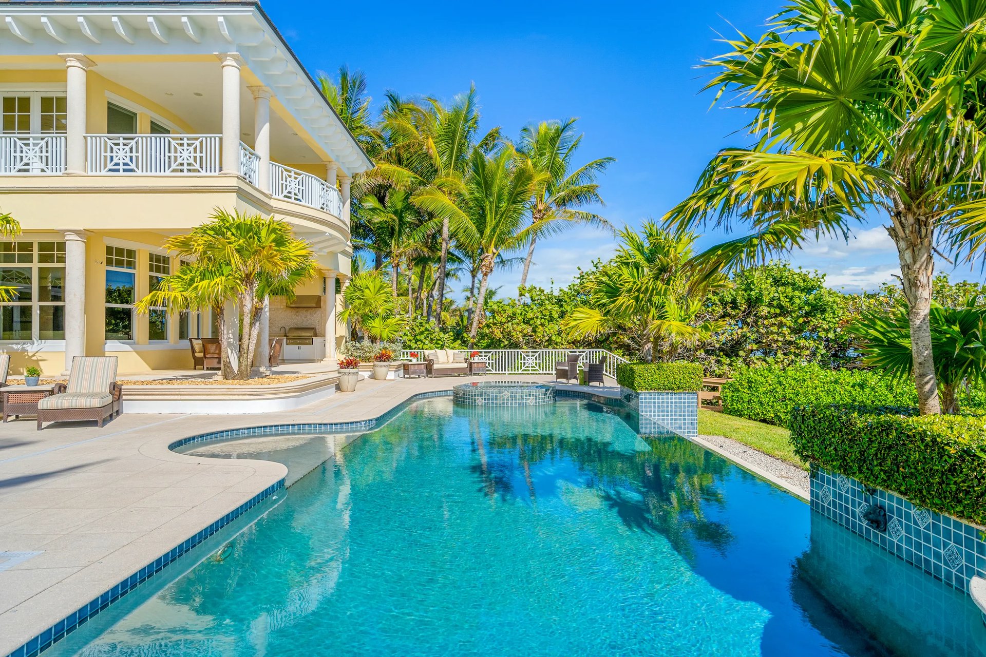 Rear elevation of a British West Indies oceanfront estate: columned lanai, deep verandas, hipped roof, and the Atlantic beyond