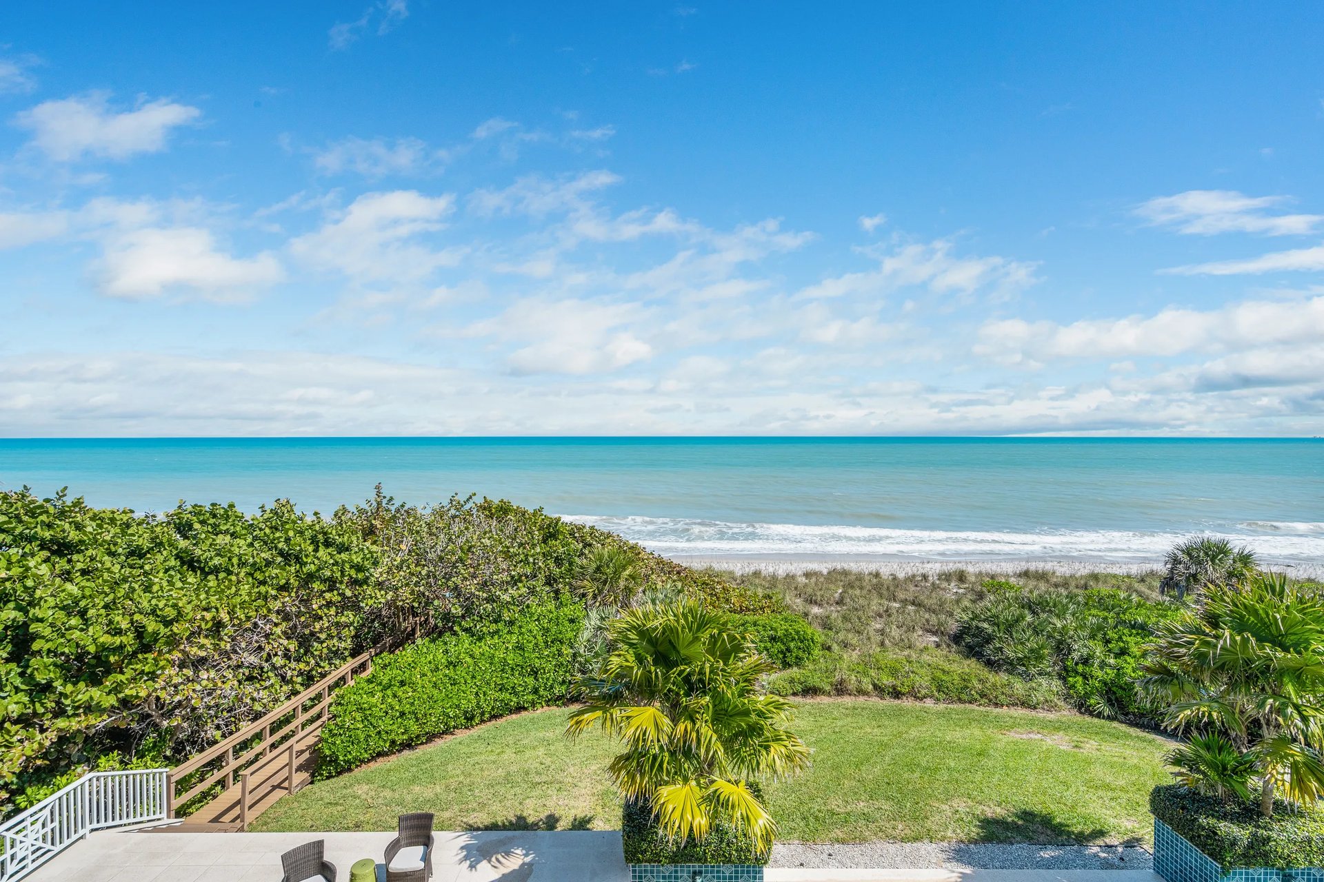 Second-floor balcony view across the rear lawn and pool to the Atlantic at a Vero Beach oceanfront estate