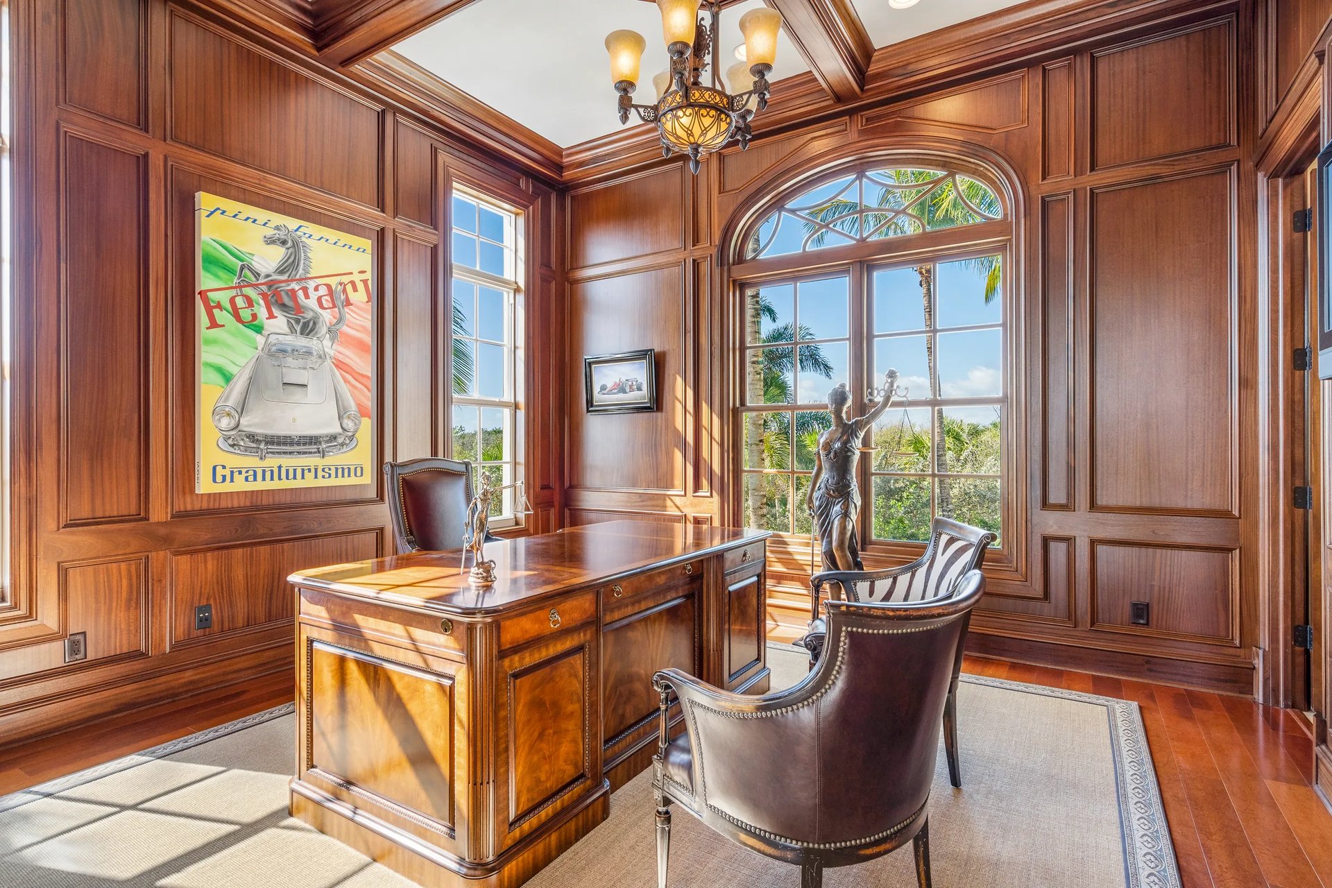 Wood-paneled study with leather desk, built-in bookcases, and an arched window. Interior at 211 Beachside Drive