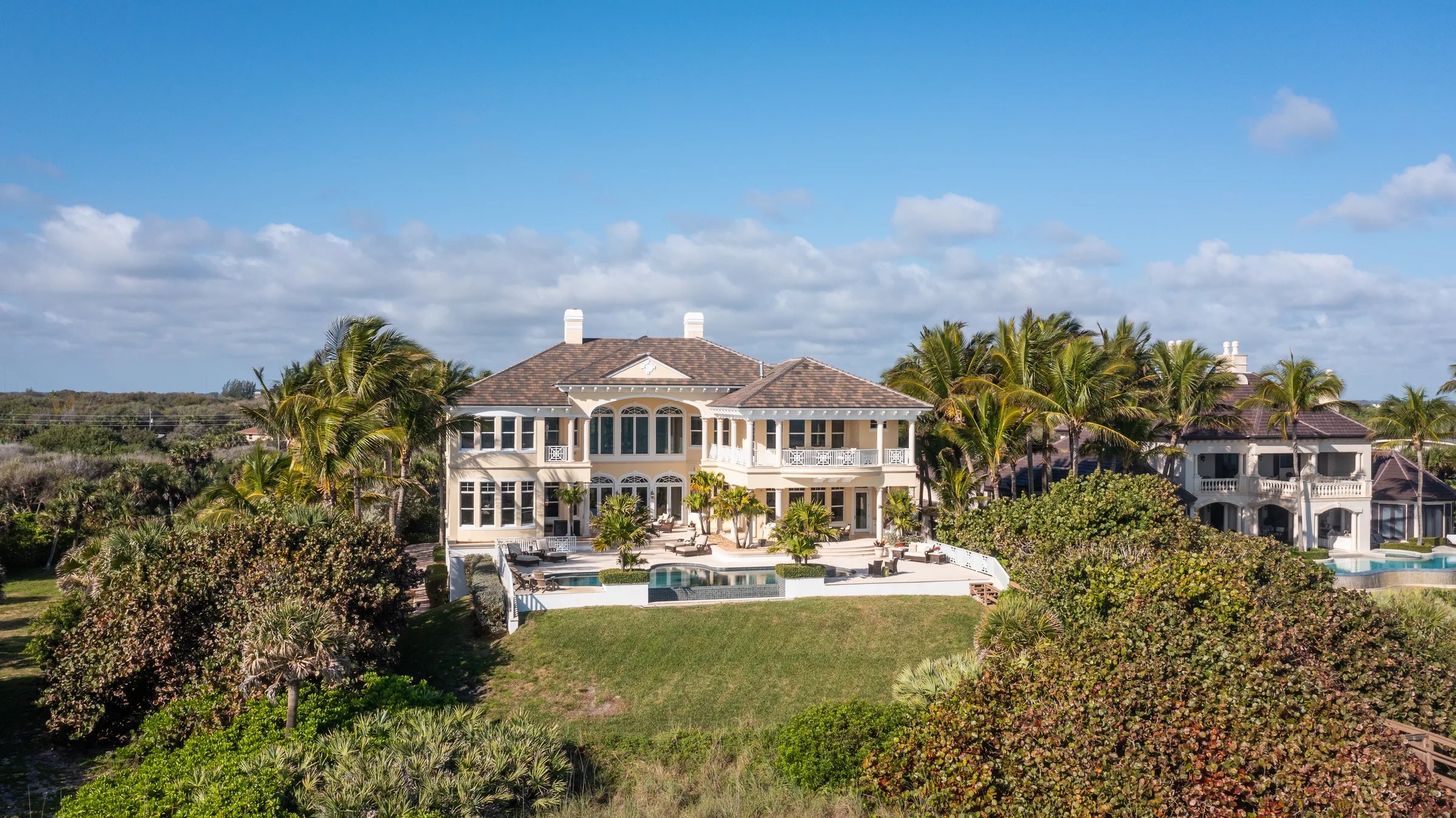 Mid-distance rear aerial of 211 Beachside Drive estate showing the pool deck, dune line, and Atlantic shoreline at Orchid Island