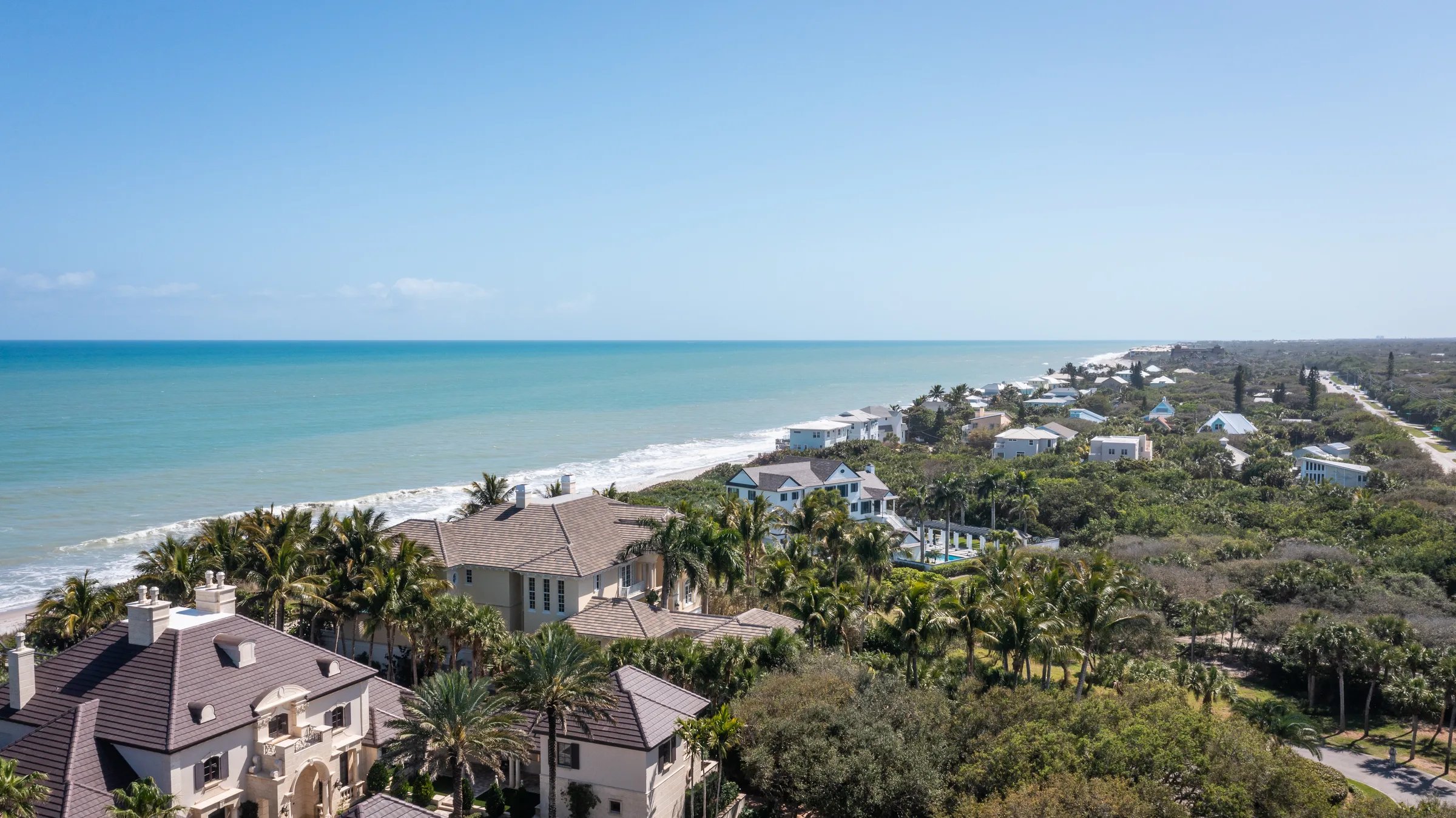 Aerial view of 211 Beachside Drive estate with its oceanfront lawn, infinity pool, and Atlantic shoreline at Orchid