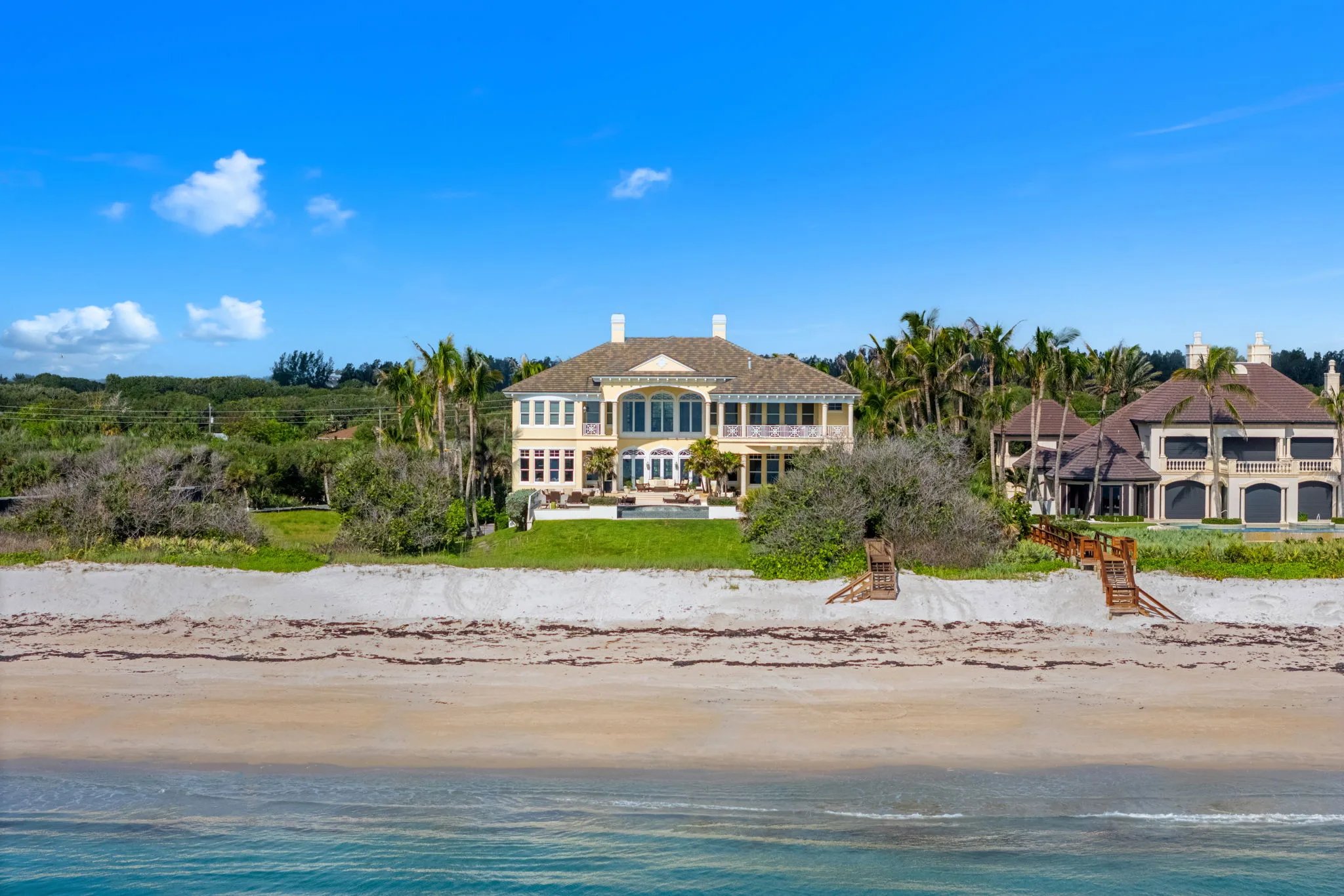 Low aerial of the estate seen from the surf, showing the dune line and pool terrace