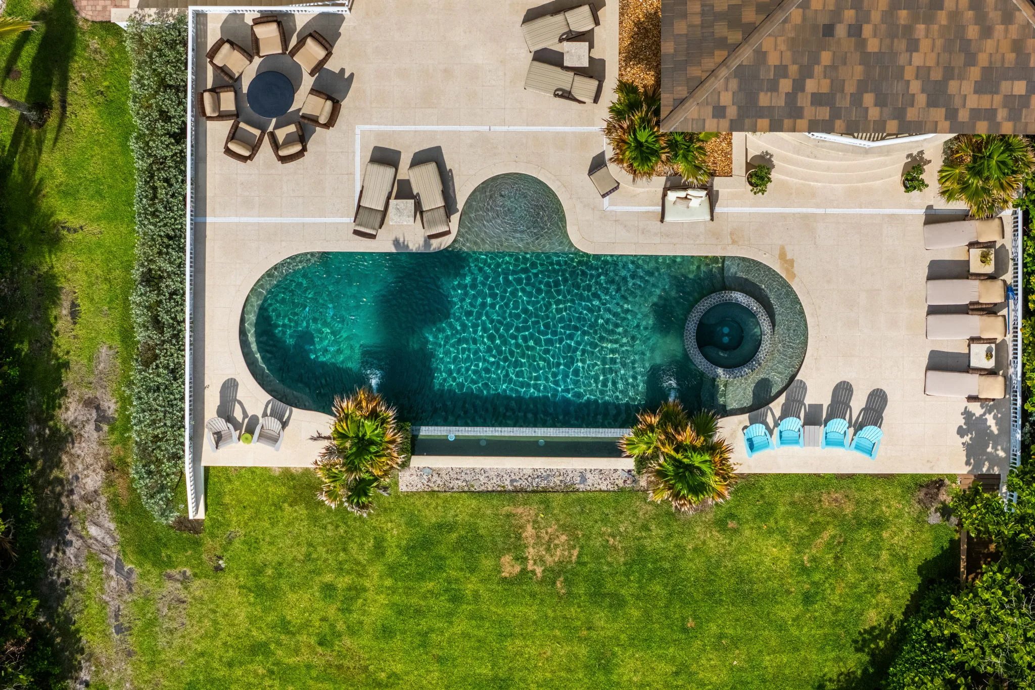 Top-down aerial of pool and spa with travertine deck, chaises, and Adirondacks