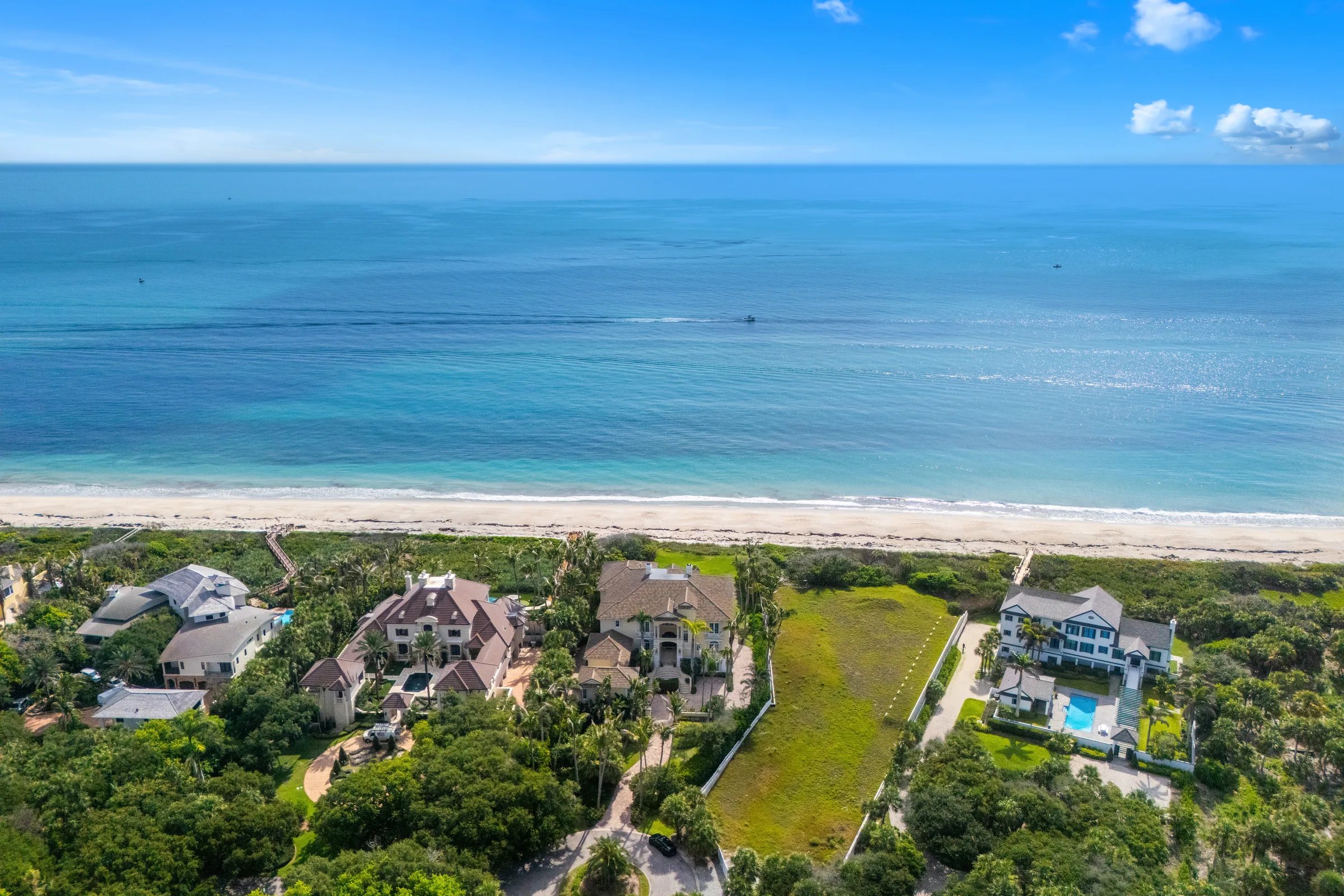 Aerial from offshore showing Atlantic shoreline and the row of estates including 211 Beachside Drive in Orchid