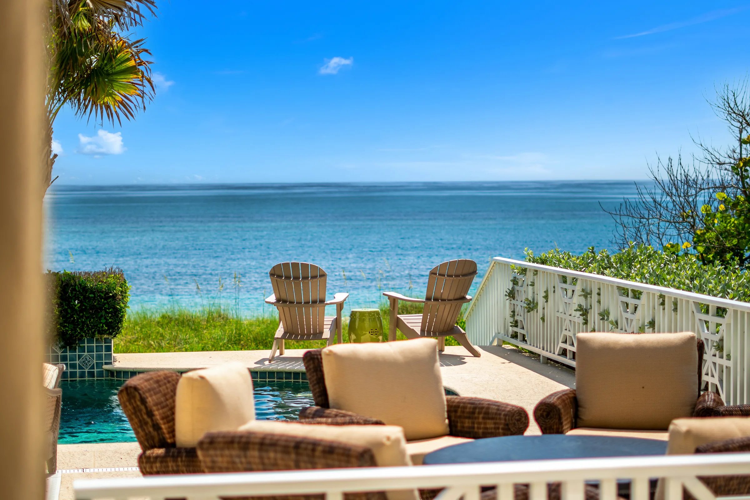 Covered lanai loungers frame Adirondack chairs above the Atlantic horizon