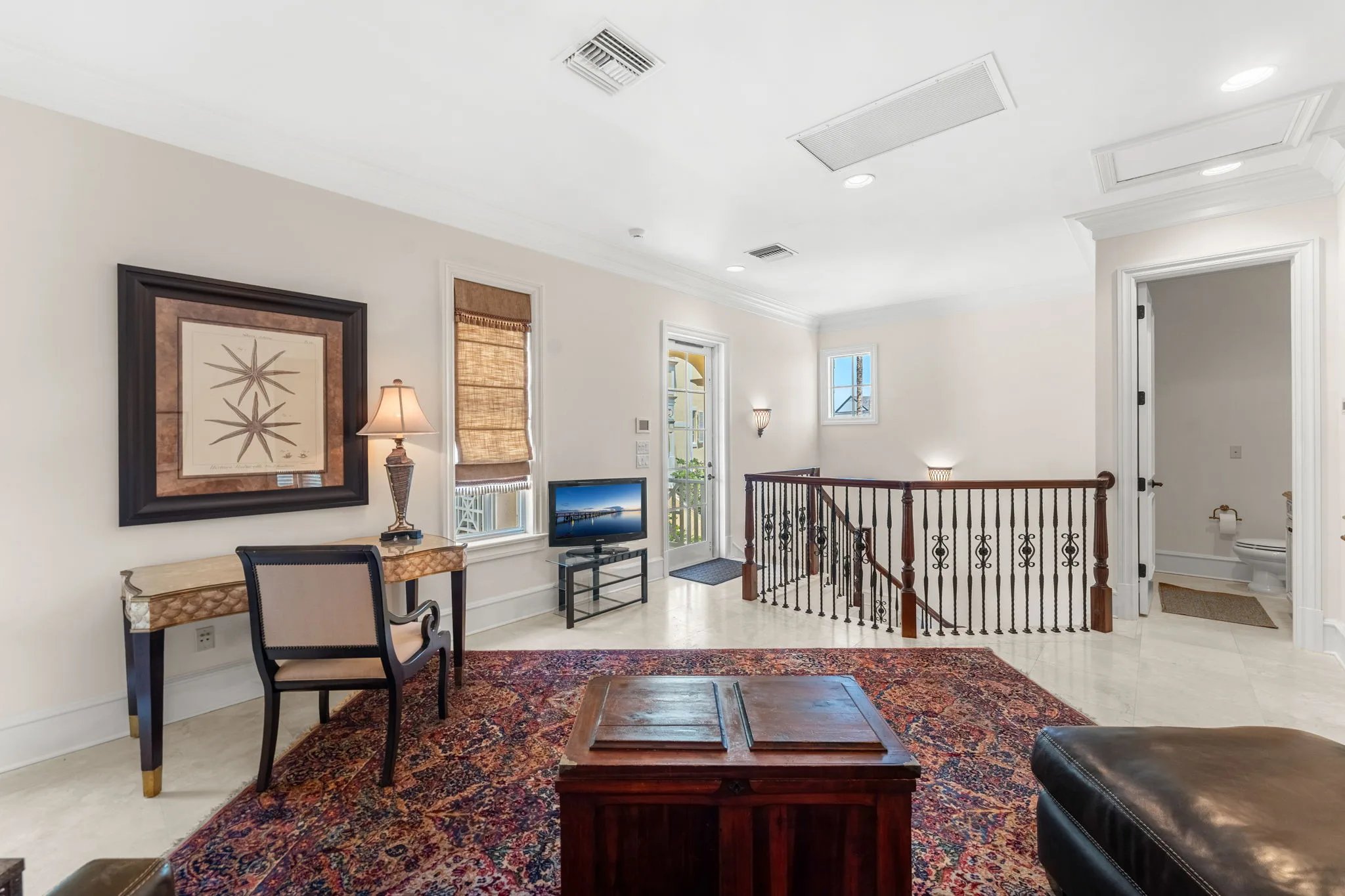 Upper landing den with iron staircase railing and seaward porch door