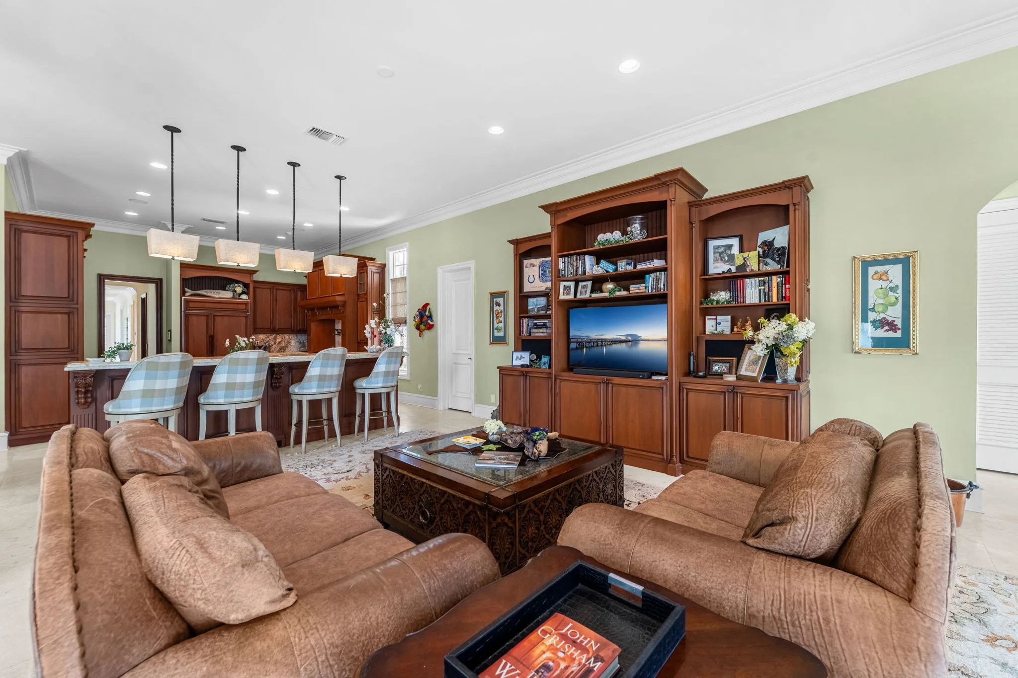 Family room with built-in cherry bookcase, leather sectional, and kitchen bar seating in the gathering wing