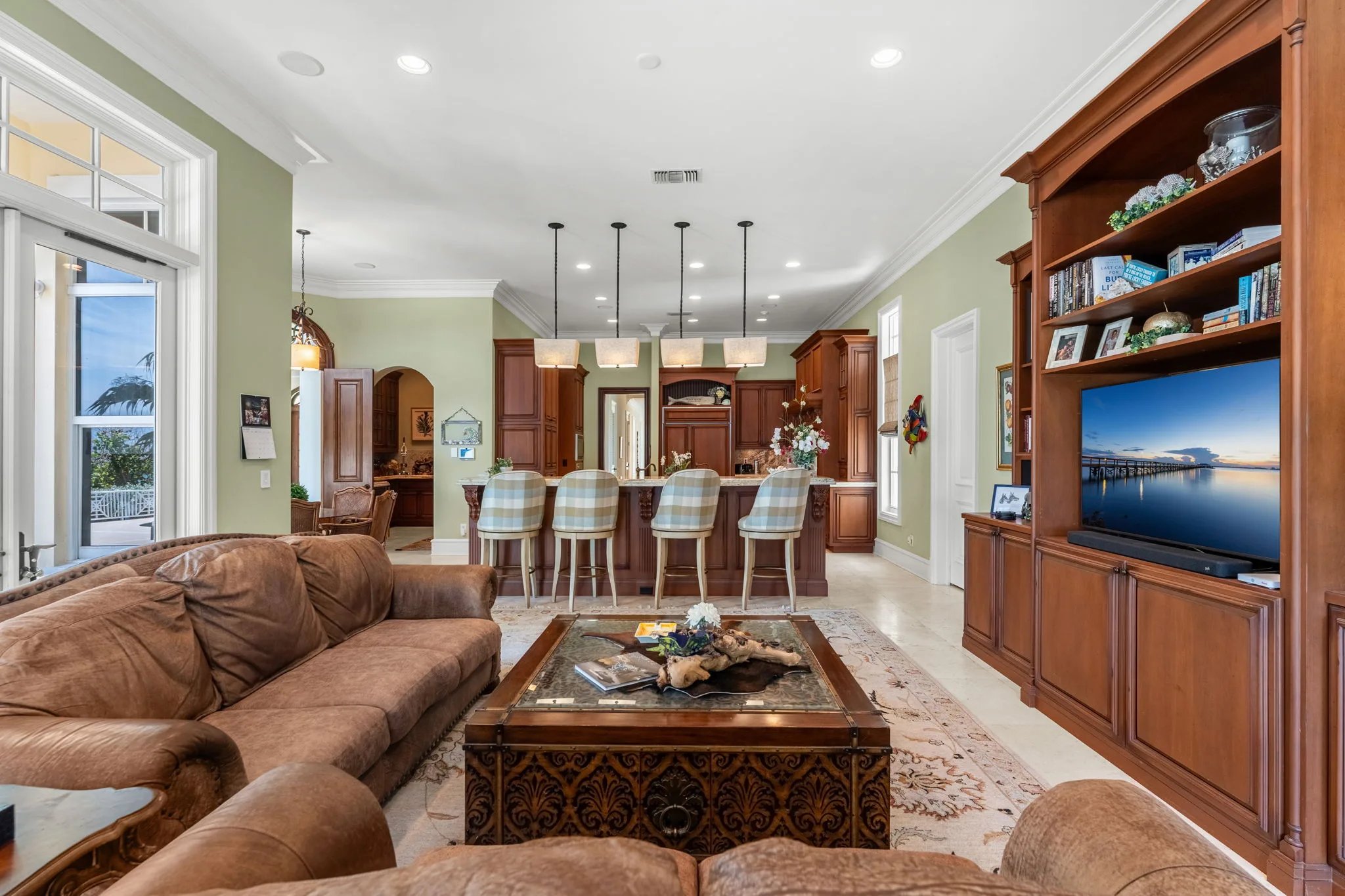 Sage family room with leather sofas, breakfast bar seating, and open kitchen view beyond