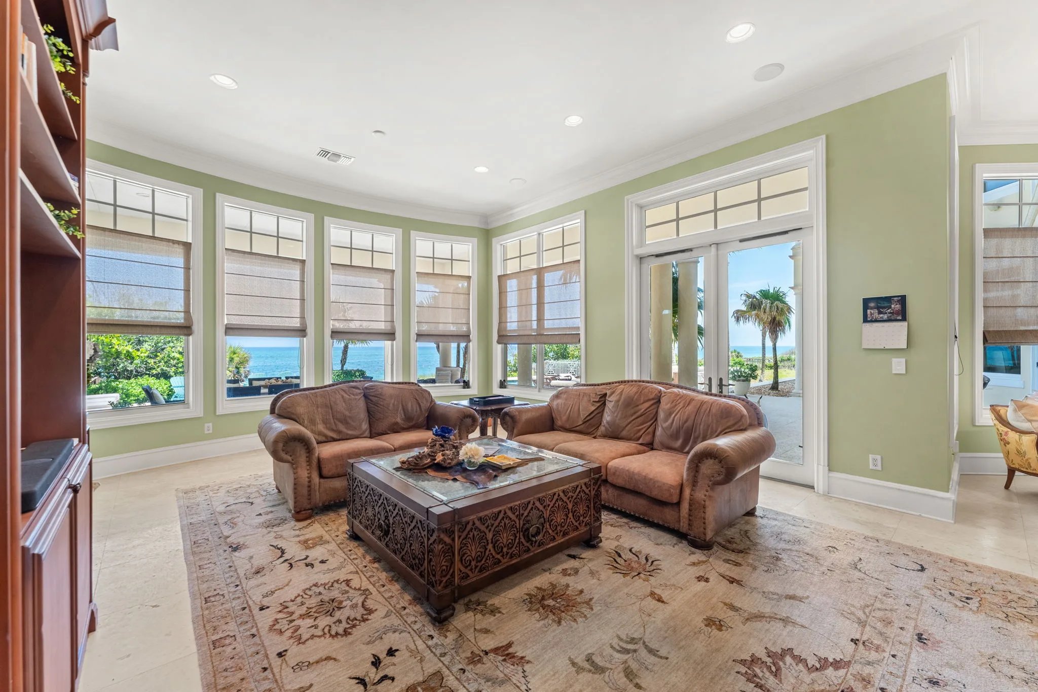 Green family room with curved bay window wall framing Atlantic horizon