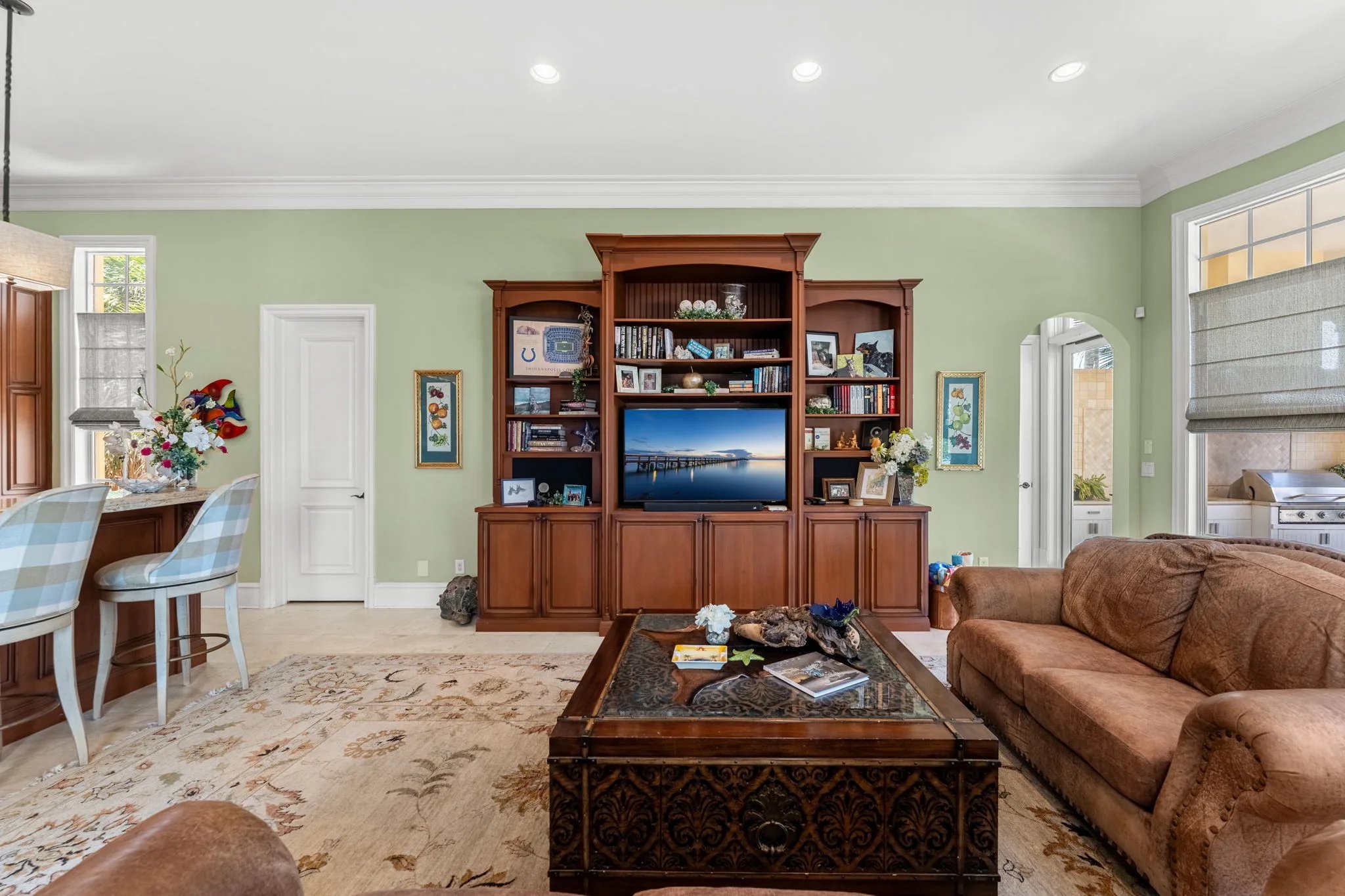 Sage family room with carved cherry entertainment built-in, leather seating and oriental rug