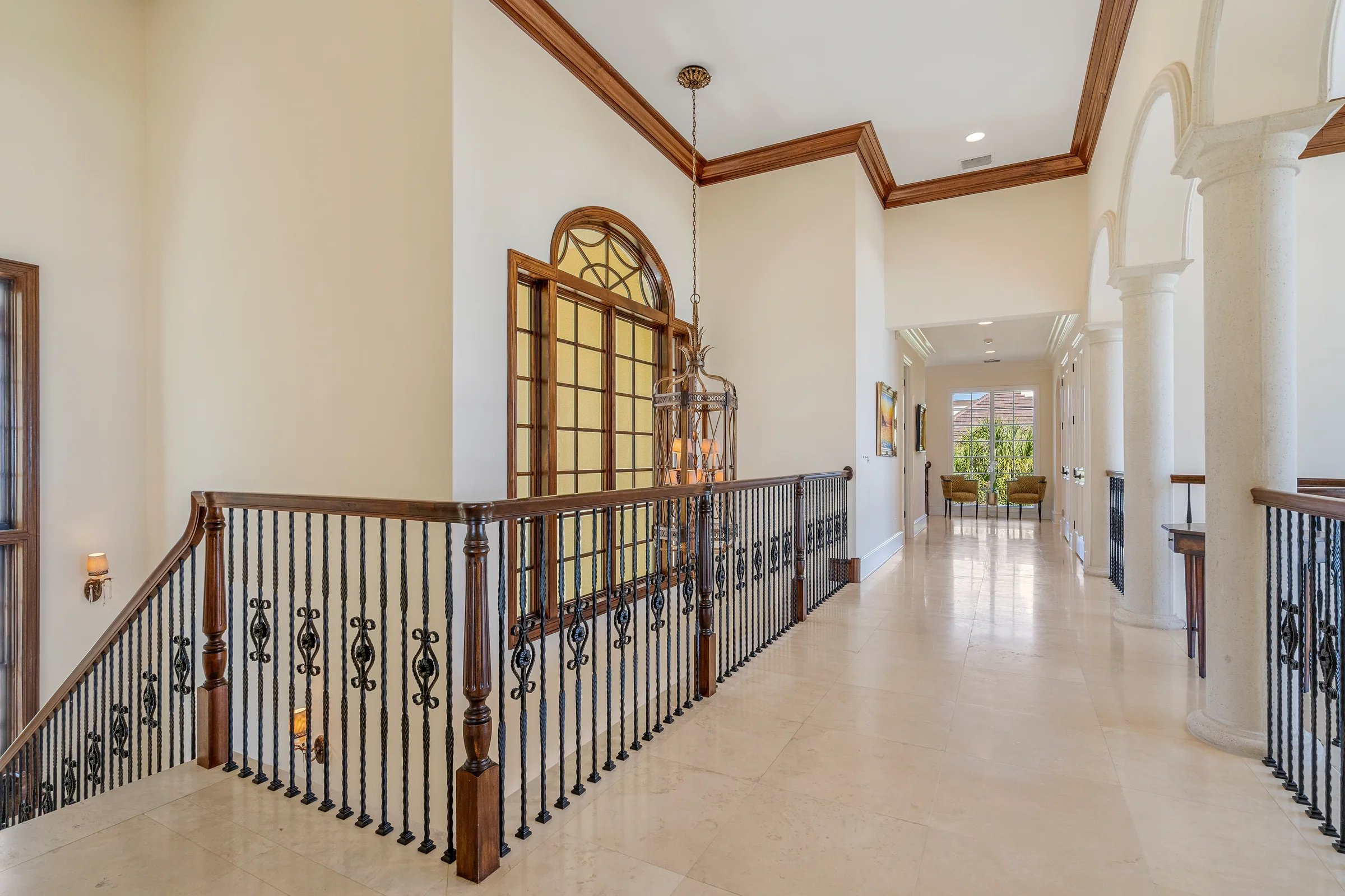 Long second-floor hallway with wrought-iron balustrade and marble floors at the 211 Beachside Drive estate
