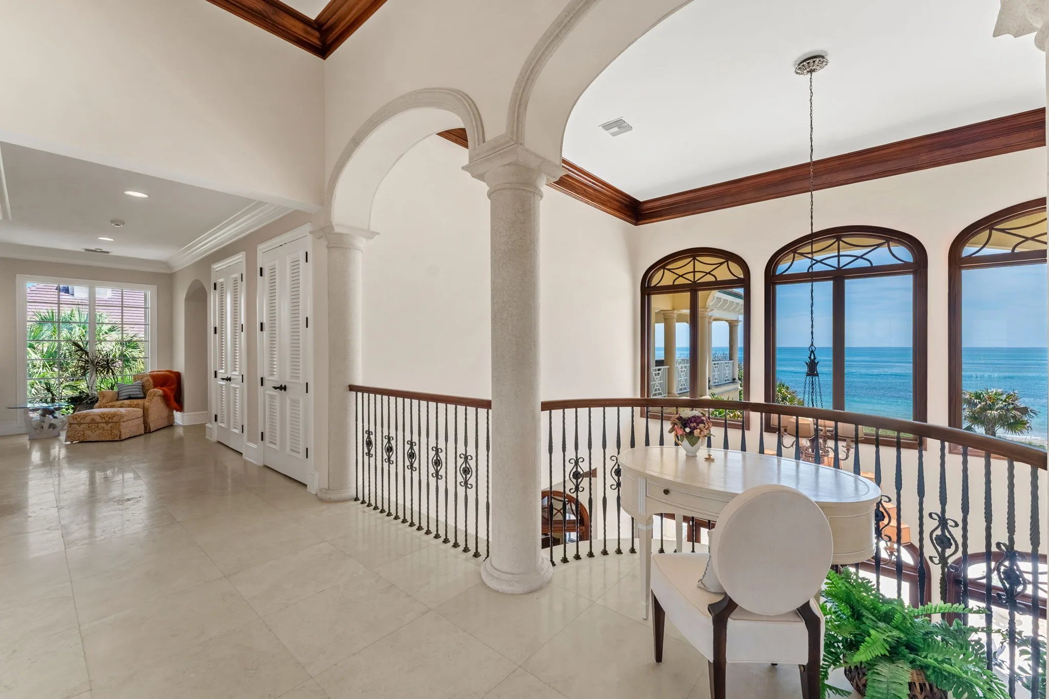Upper gallery with stone columns, arches, and arched windows framing the Atlantic