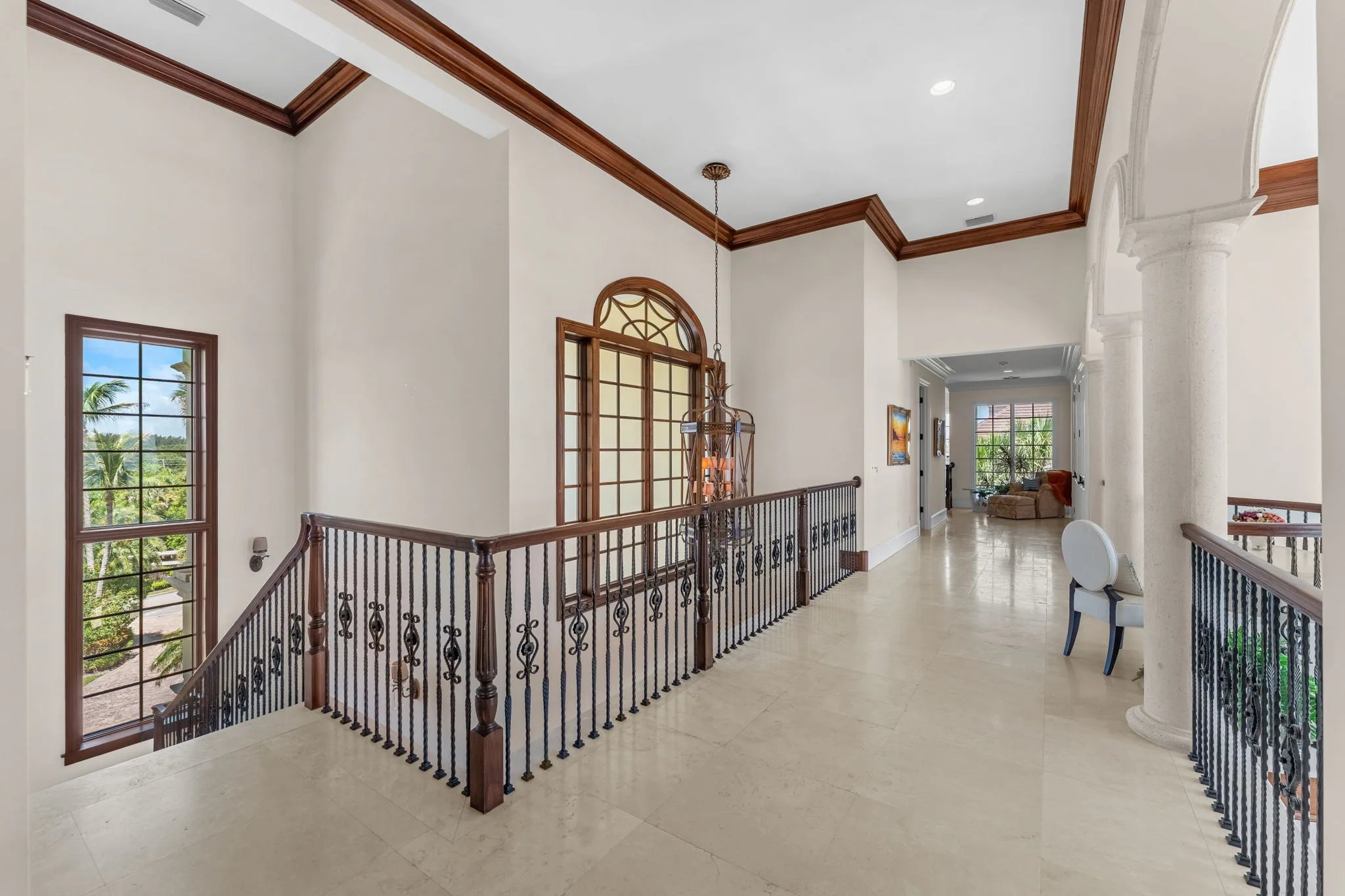 Upper gallery hallway with mahogany trim, iron balustrade, and Palladian window