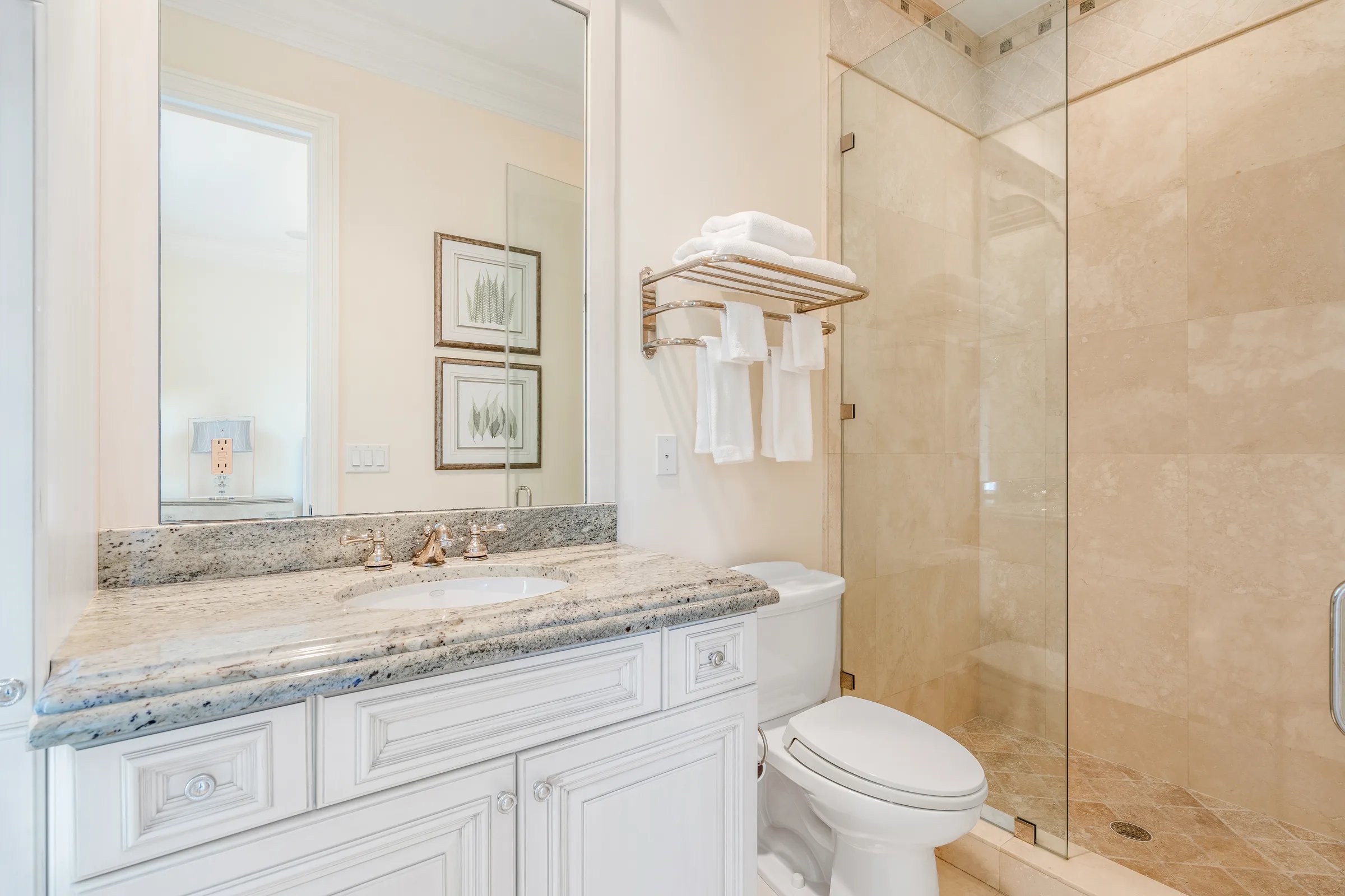 Guest ensuite bath with framed wall art, cream stone vanity, and walk-in shower