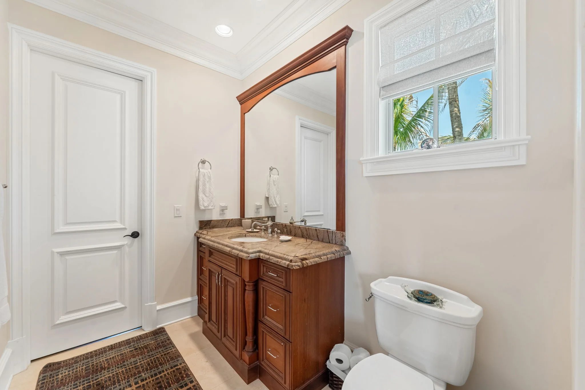 Guest bath with cherry-framed mirror, granite vanity and palm-framed transom window