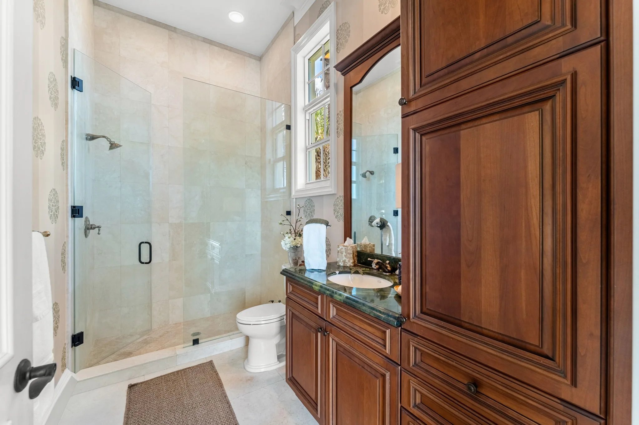 Guest bath with cherry built-in vanity, granite counter, and walk-in travertine shower