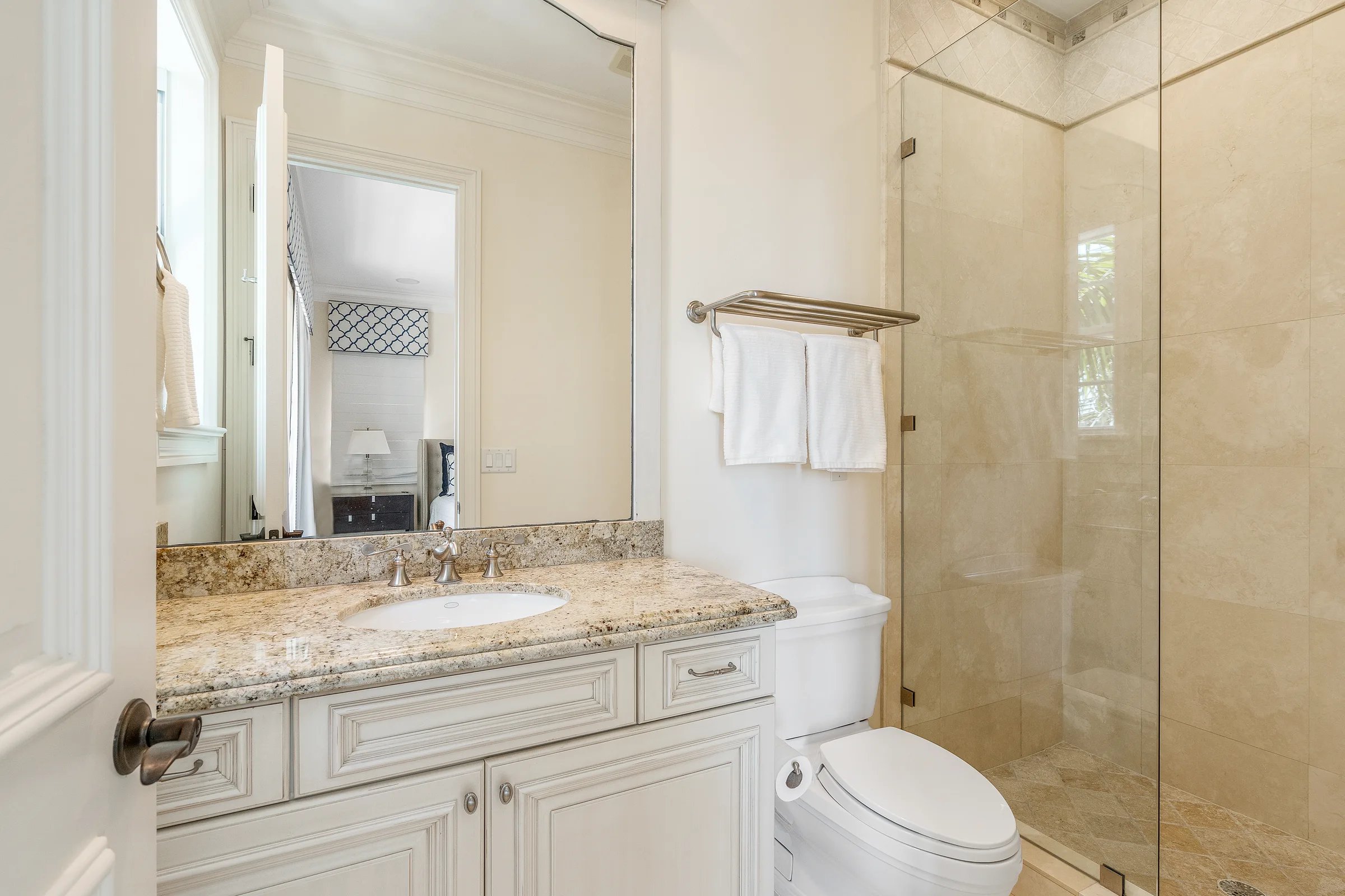 Guest ensuite bath off the coastal bedroom, with cream stone vanity and walk-in shower