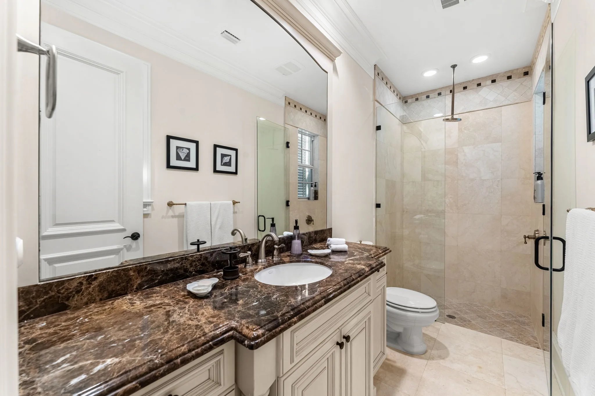 Guest bath with emperador marble vanity and travertine walk-in shower