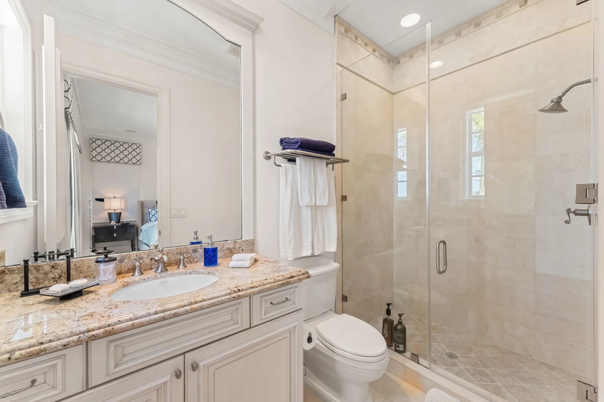Guest bath with golden granite vanity and frameless glass walk-in shower