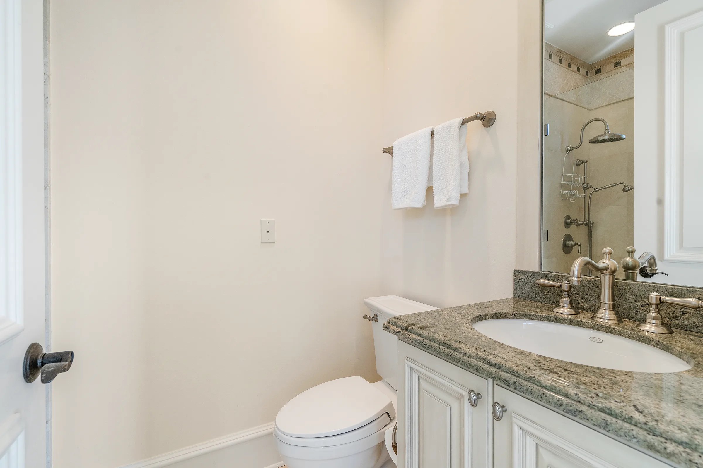 Lower-level guest bath with stone-clad walk-in shower and travertine vanity at 211 Beachside Drive in Orchid