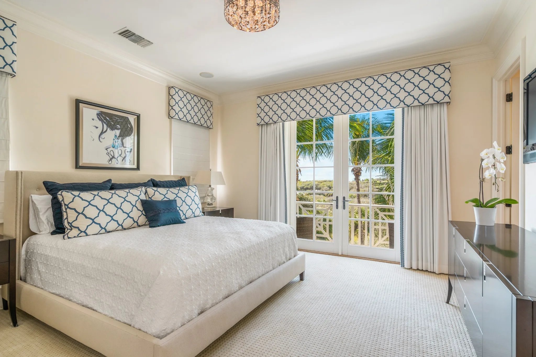 Guest bedroom in blue trellis with French doors opening to palm-lined balcony