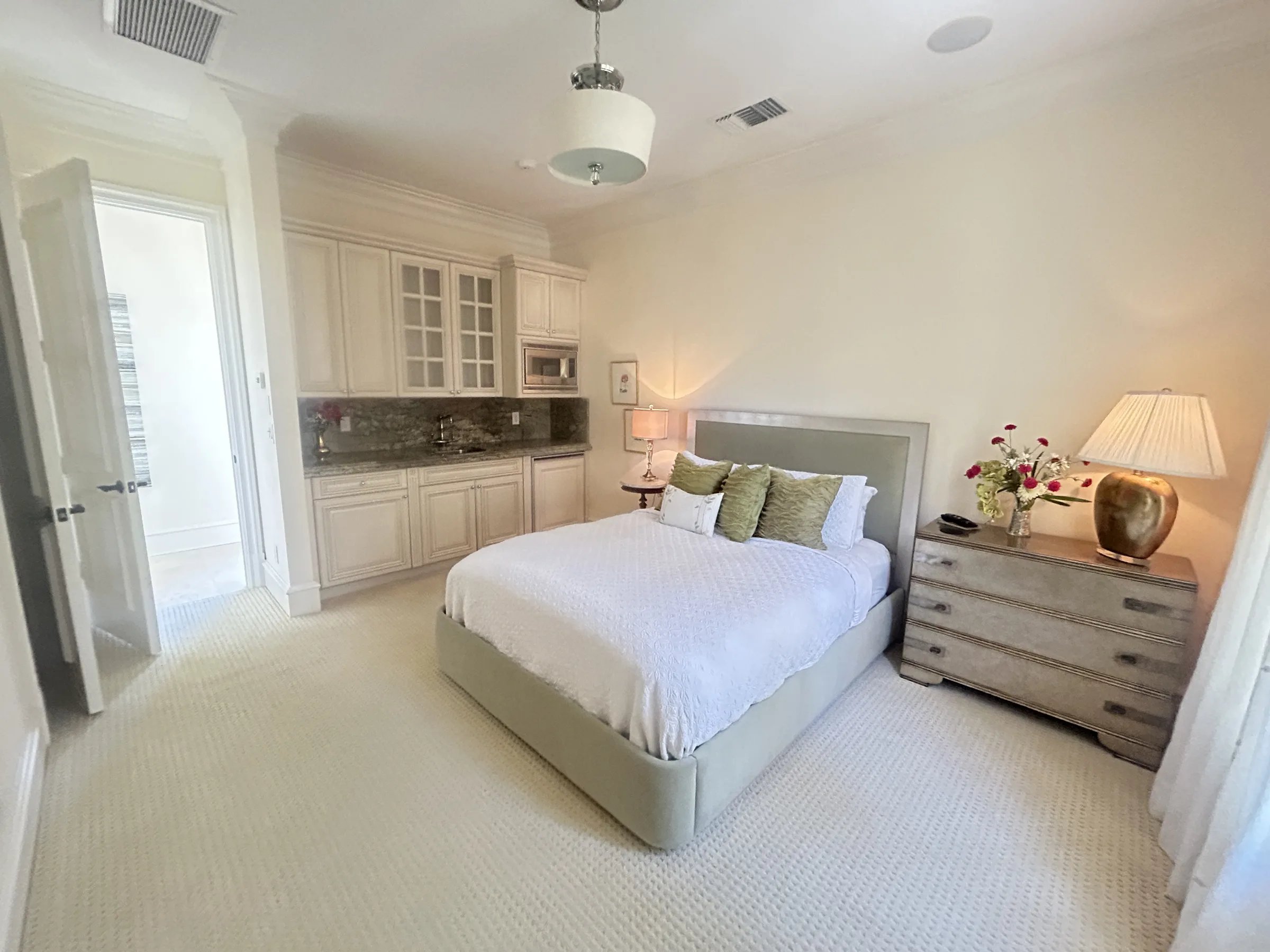 Guest bedroom with built-in kitchenette, sage upholstered bed and dressing chest