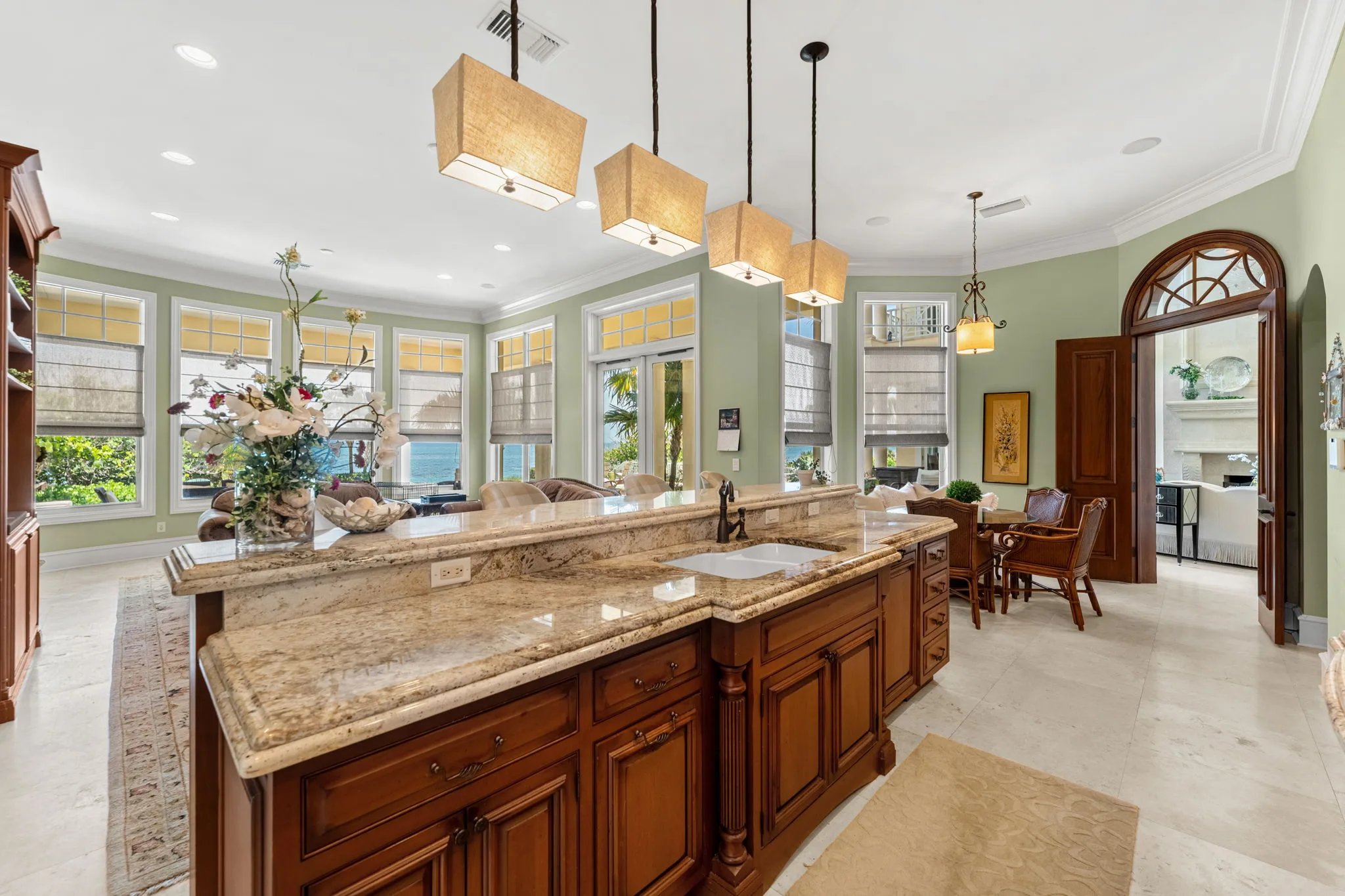 Long granite breakfast bar under four linen pendants with ocean view through bay windows