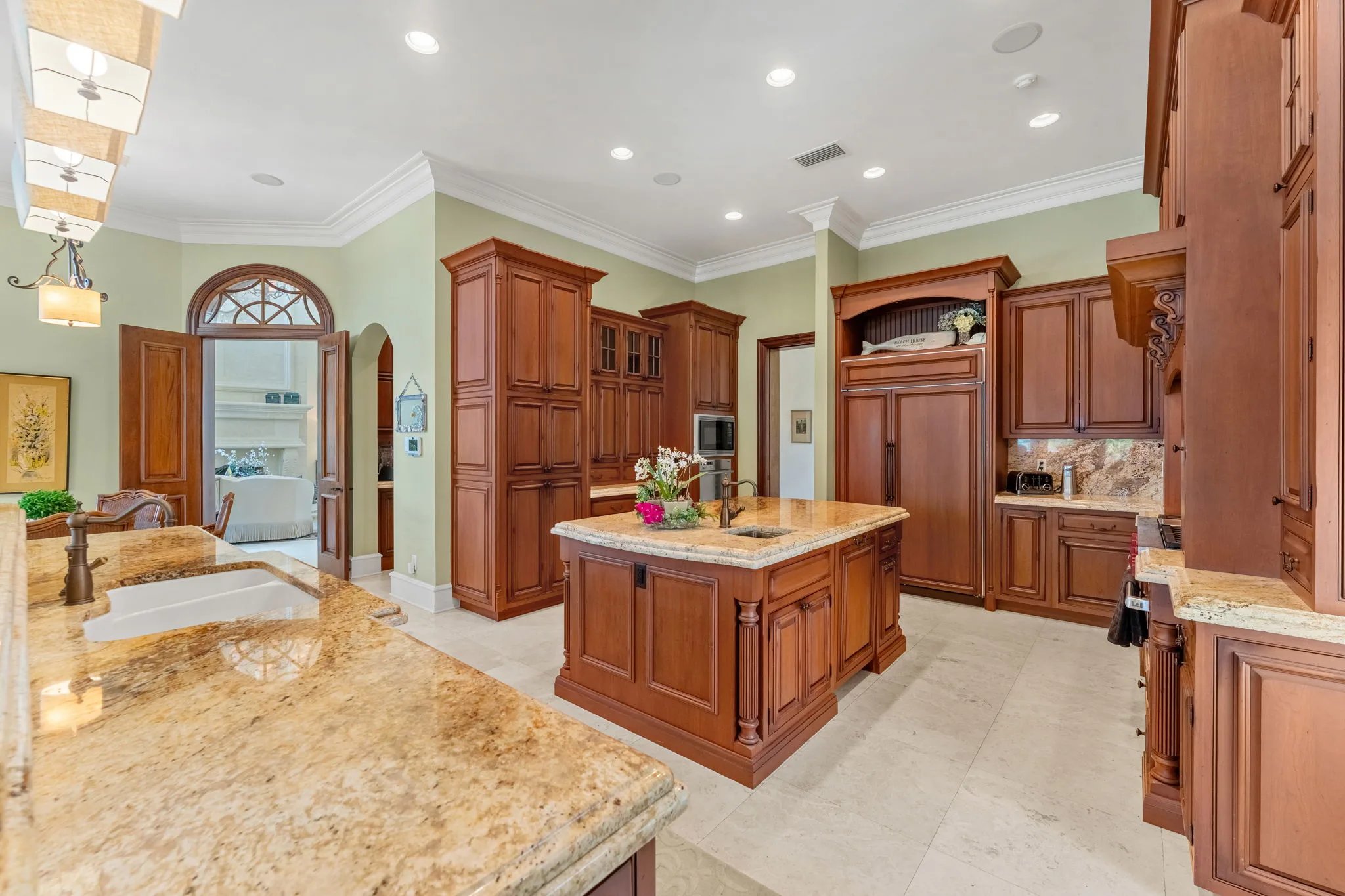 Cherry kitchen with twin granite islands and arched doorway opening to the great room