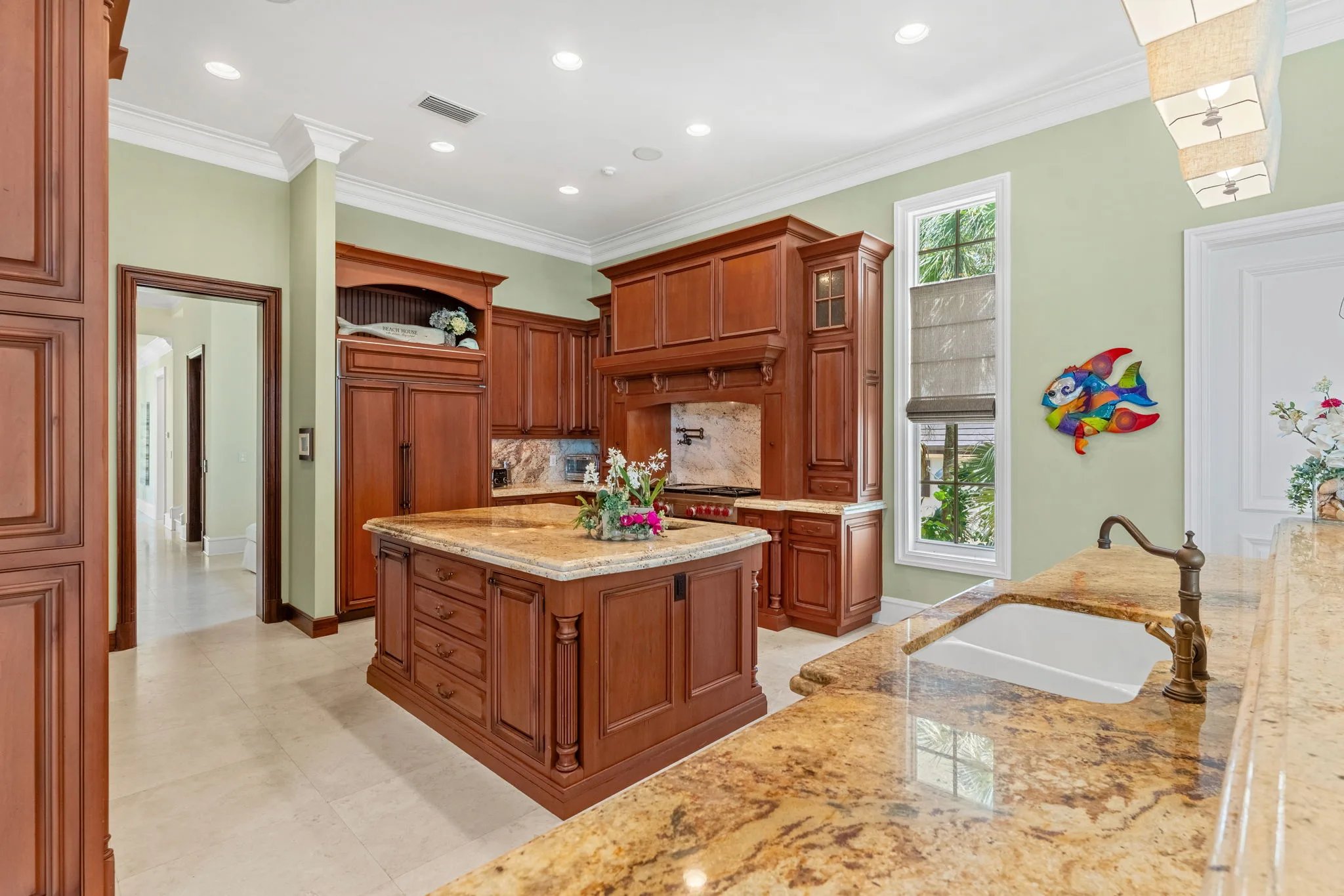 Cherry kitchen island and pro range under custom wood hood, granite counters, sage walls