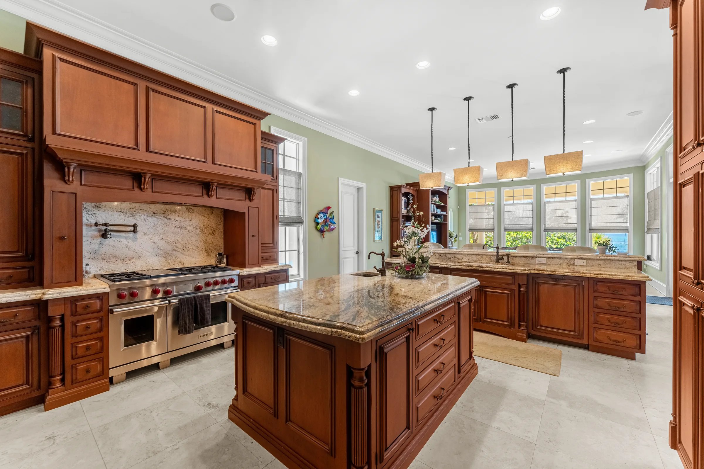 Chef's kitchen with twin granite islands, Wolf range, and pendant-lit breakfast bar