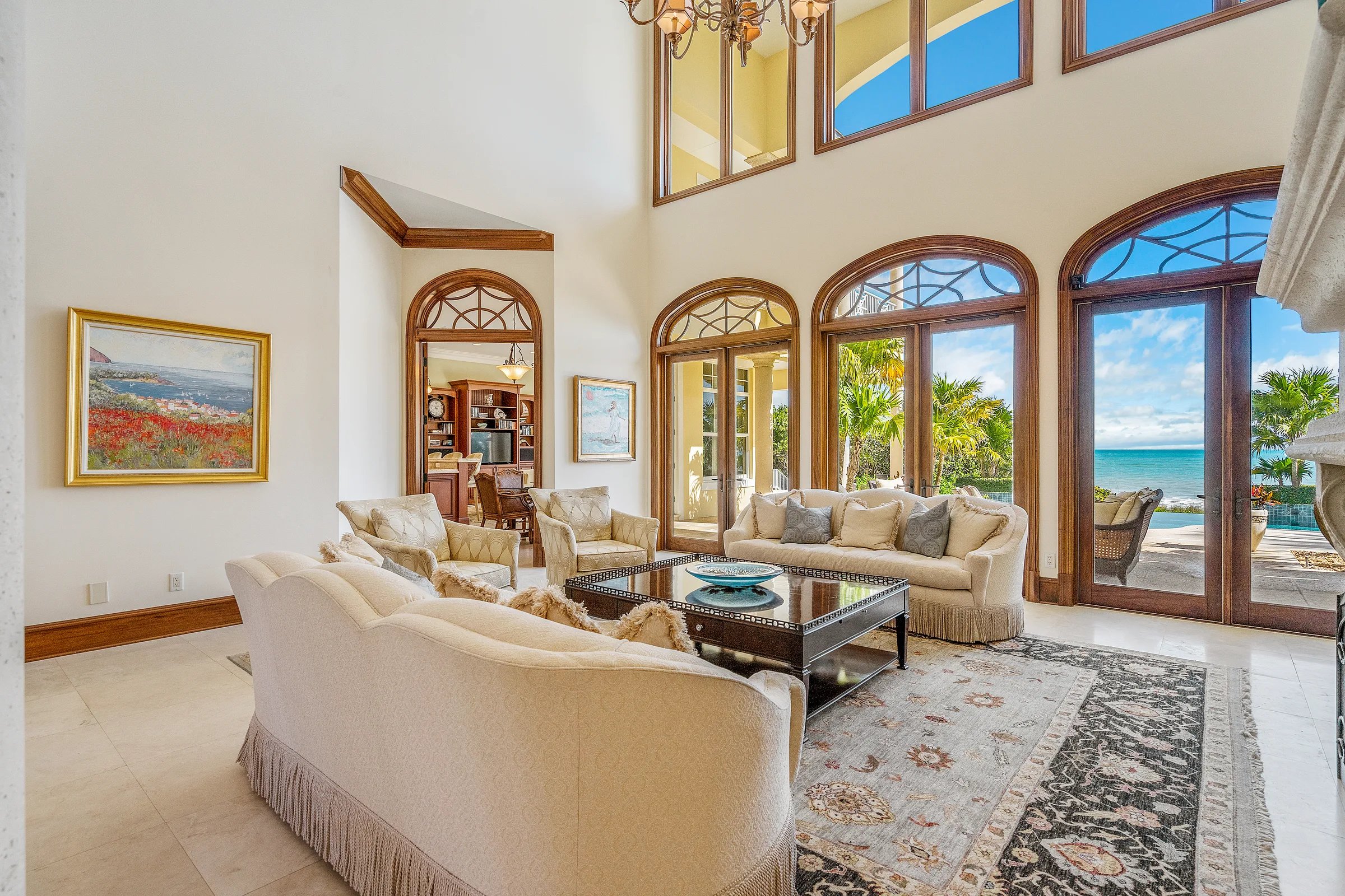 Two-story great room at 211 Beachside Drive with sofas facing the Atlantic horizon framed through arched windows