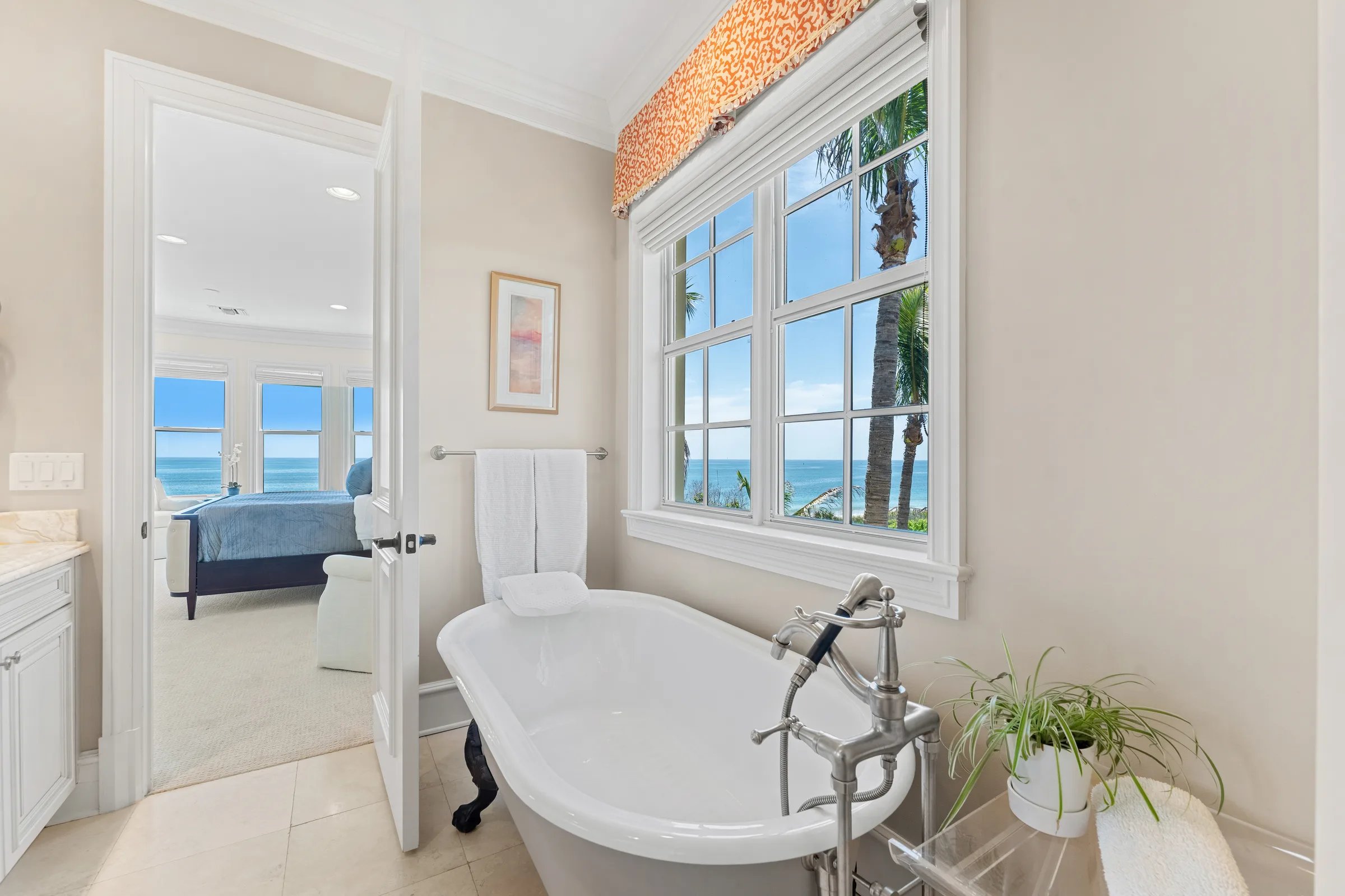 Freestanding clawfoot soaking tub at ocean-view window beside owner bedroom doorway
