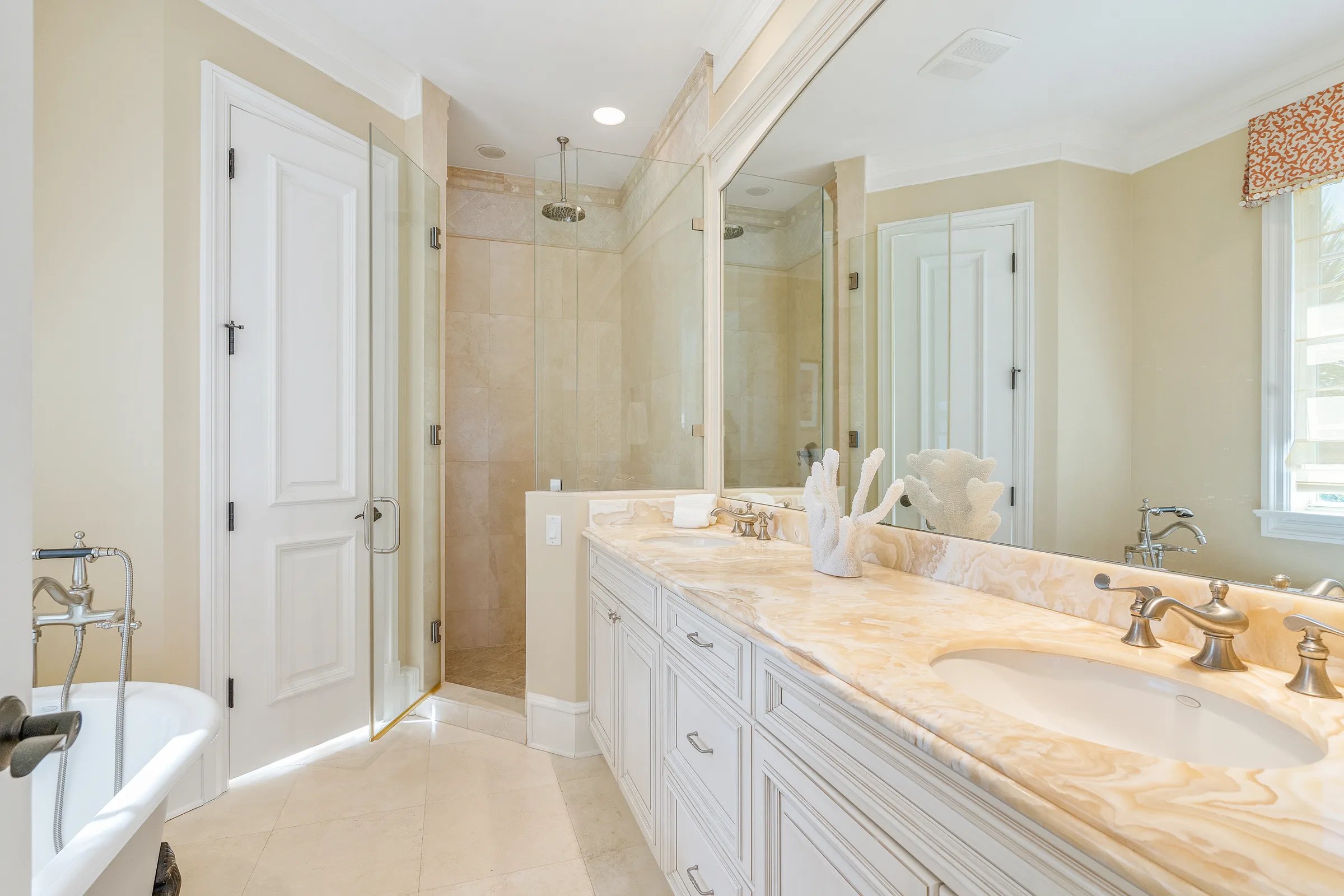 Owner's bath with pink onyx double vanity, walk-in shower, and freestanding clawfoot tub