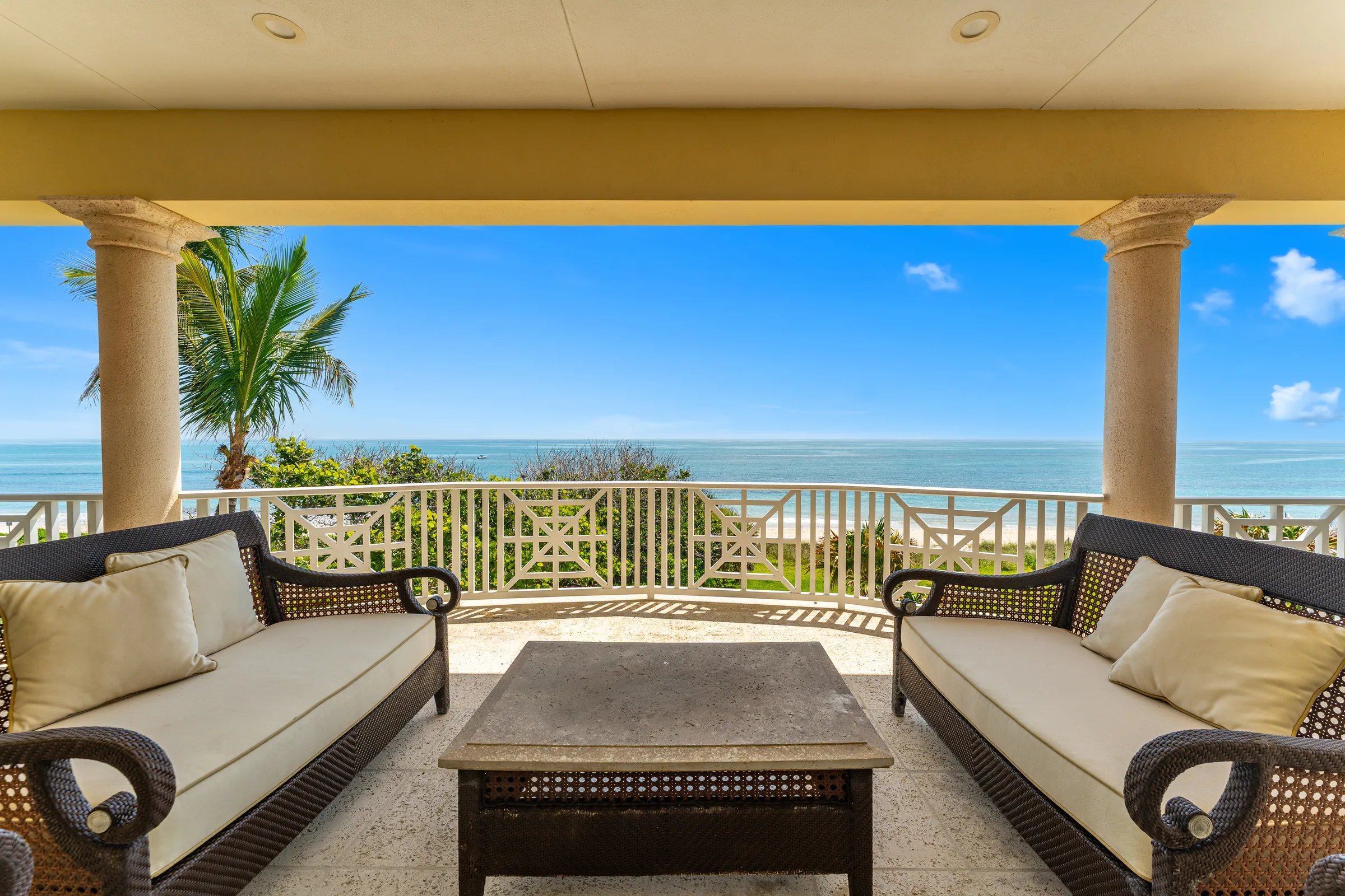 Wicker daybeds line the covered owner porch above the Atlantic horizon