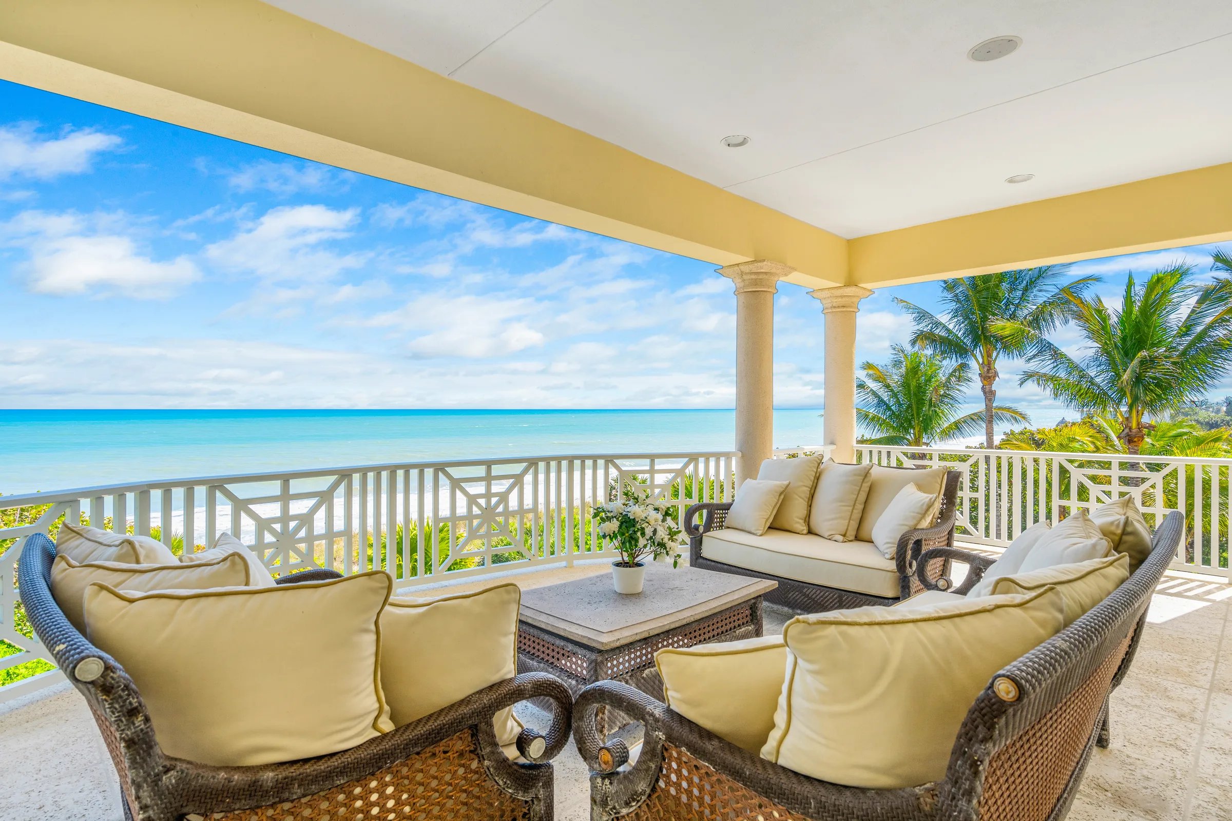 Covered owner-suite porch lounge with rattan seating and Atlantic horizon view at 211 Beachside Drive, Orchid Island
