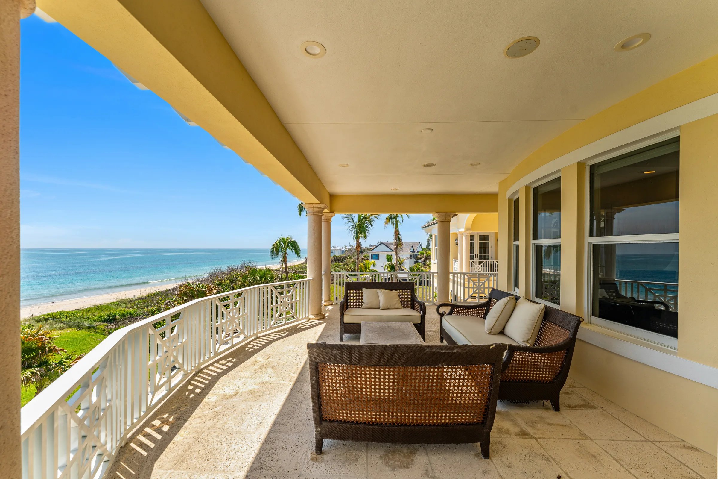 Upper covered owner's porch with caned wicker seating and sweeping Atlantic Ocean horizon over the Orchid Island shoreline