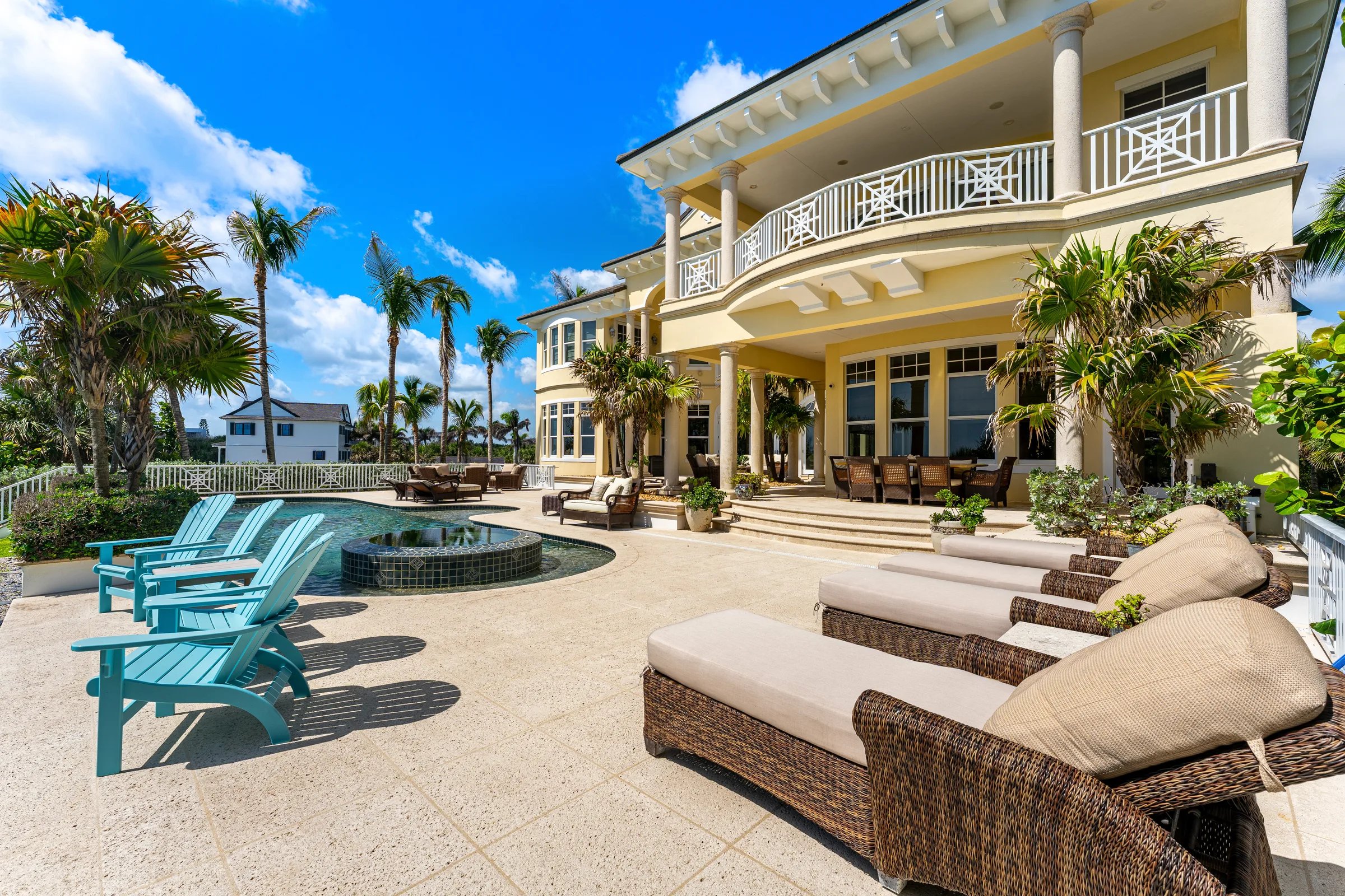 Travertine pool deck with chaise lounges, spa, and curved balconies above