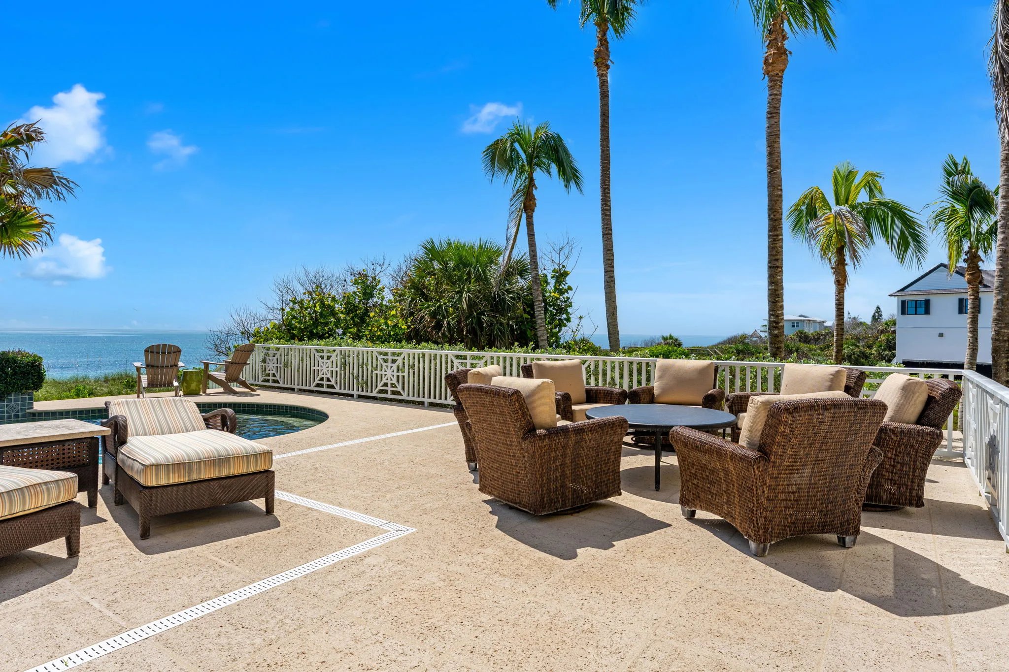 Pool deck lounge with wicker seating, plunge pool, and palms framing the Atlantic horizon