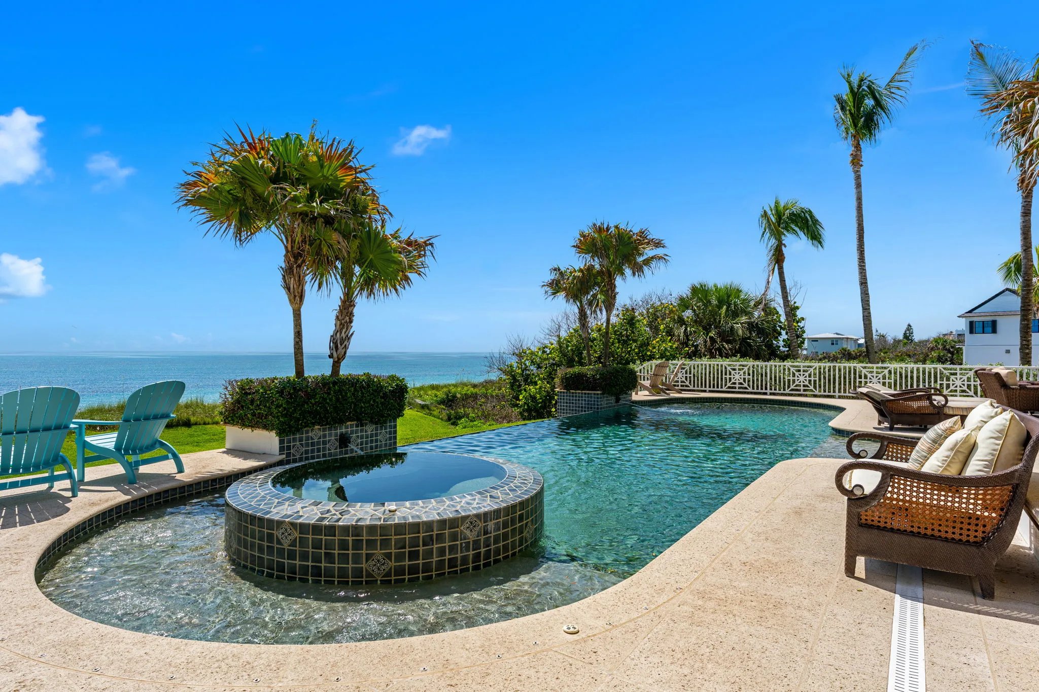 Mosaic-tiled spa beside infinity-edge pool framed by tropical palms over the Atlantic