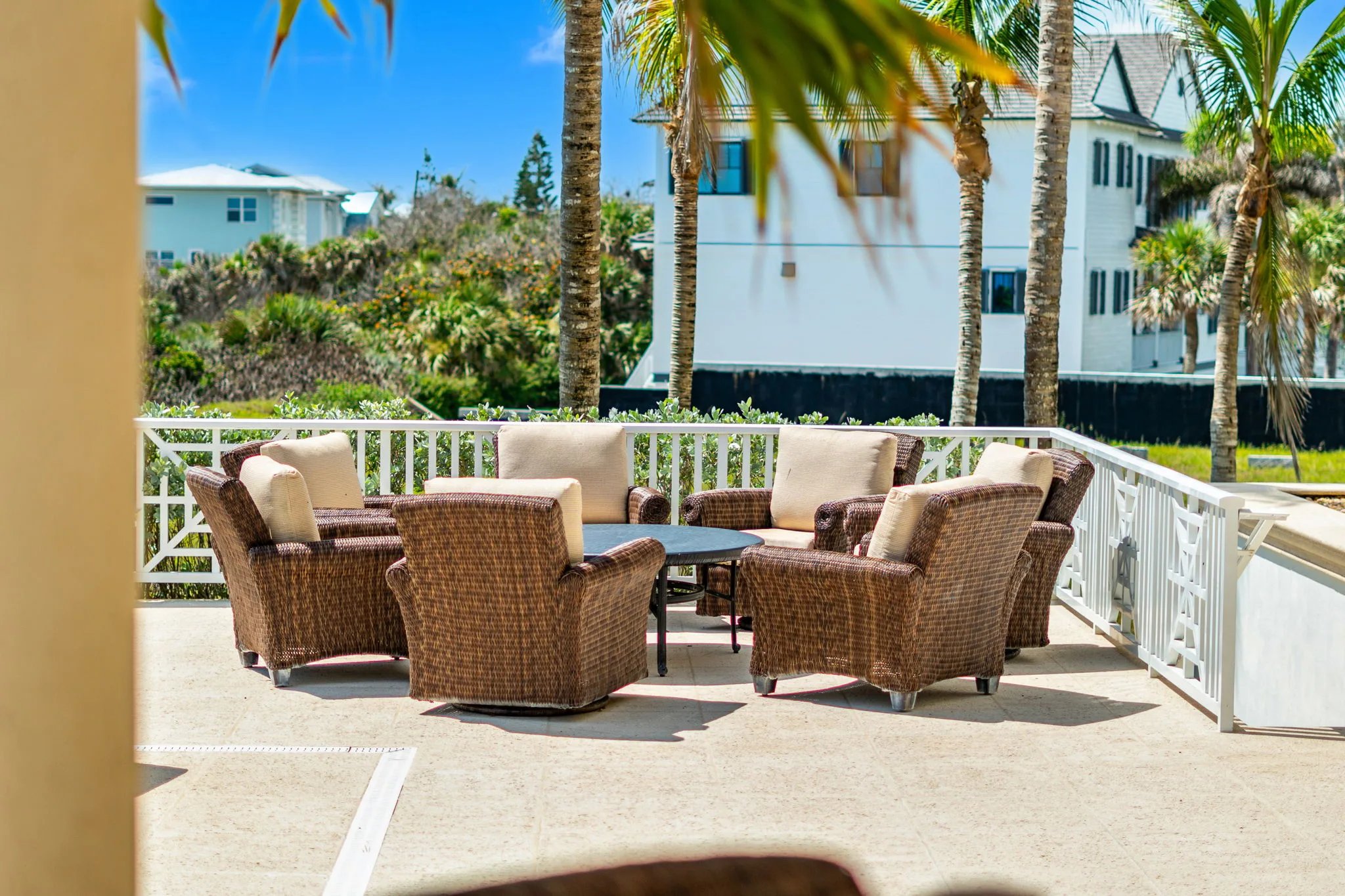 Wicker armchairs ringed around a stone table on the pool-side terrace