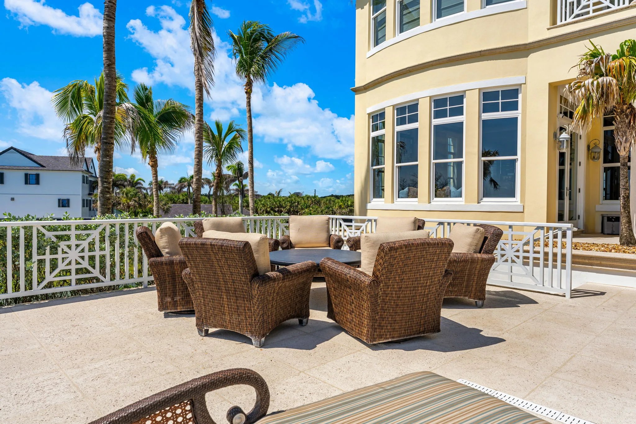 Wicker conversation circle on pool terrace beneath the curved bay of the residence