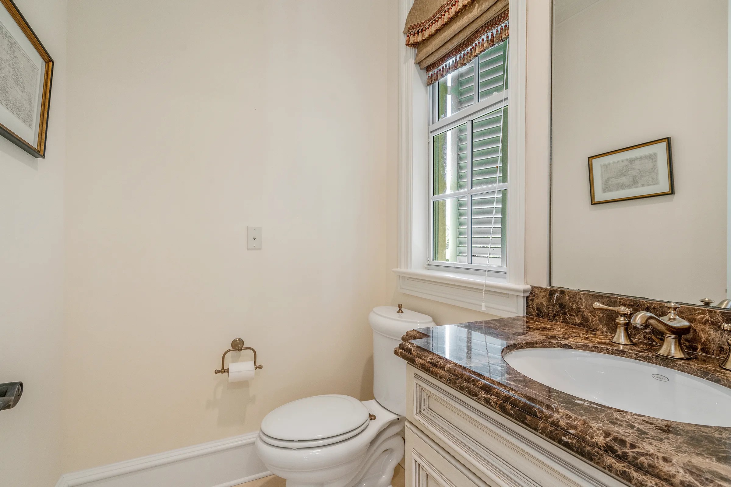 First-floor powder room with patterned wallpaper and marble vanity at 211 Beachside Drive in Orchid, Florida