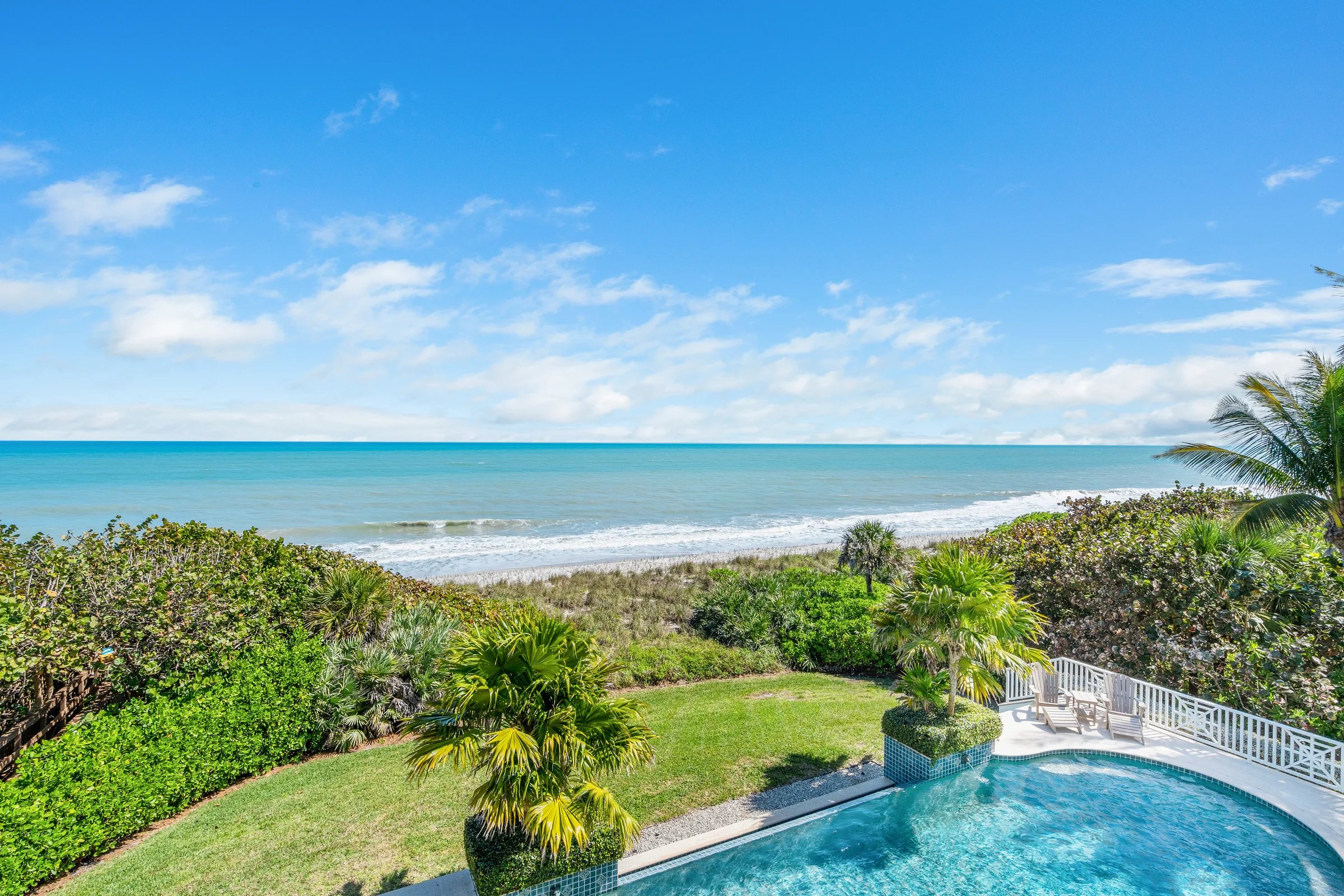 High vantage of rear lawn, pool, and ocean