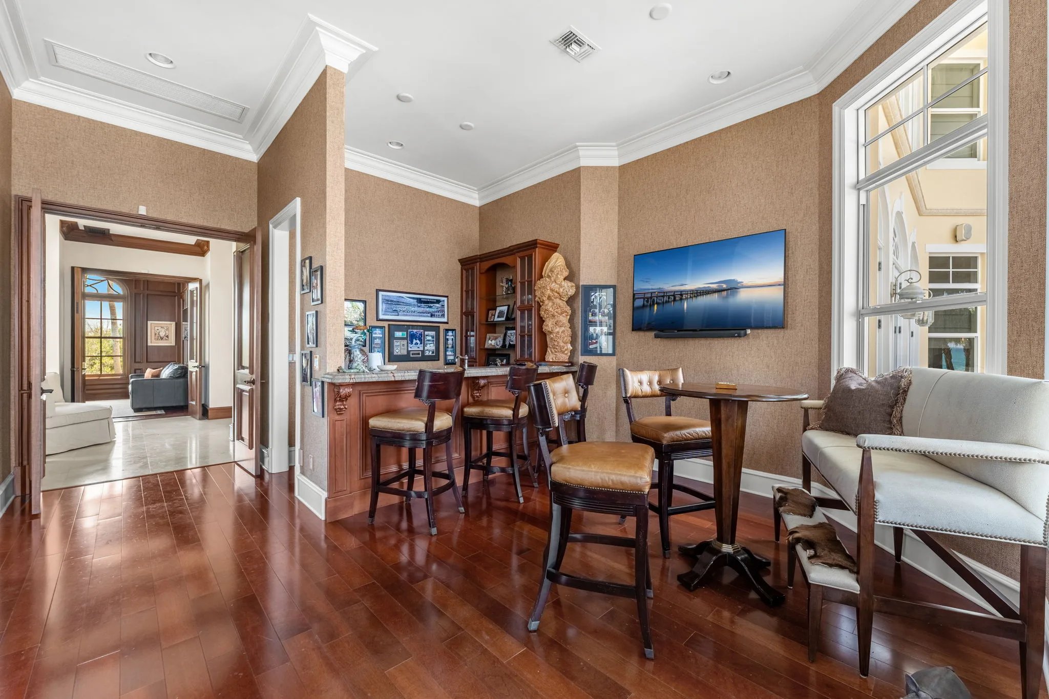 Study antechamber with built-in bar, leather stools, and view through to the study