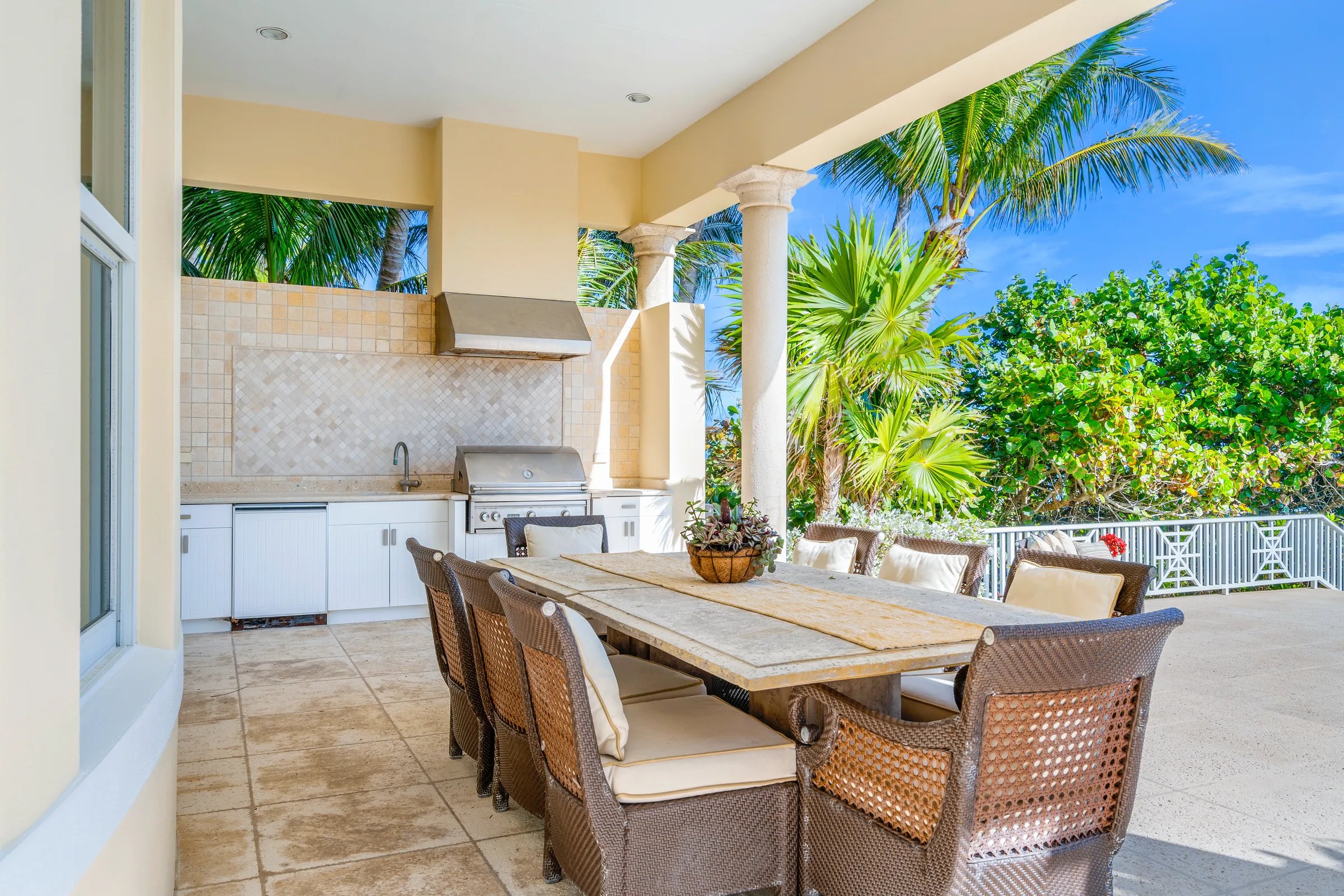 Covered summer kitchen with travertine dining table on the oceanfront lanai at 211 Beachside Drive, Orchid Island